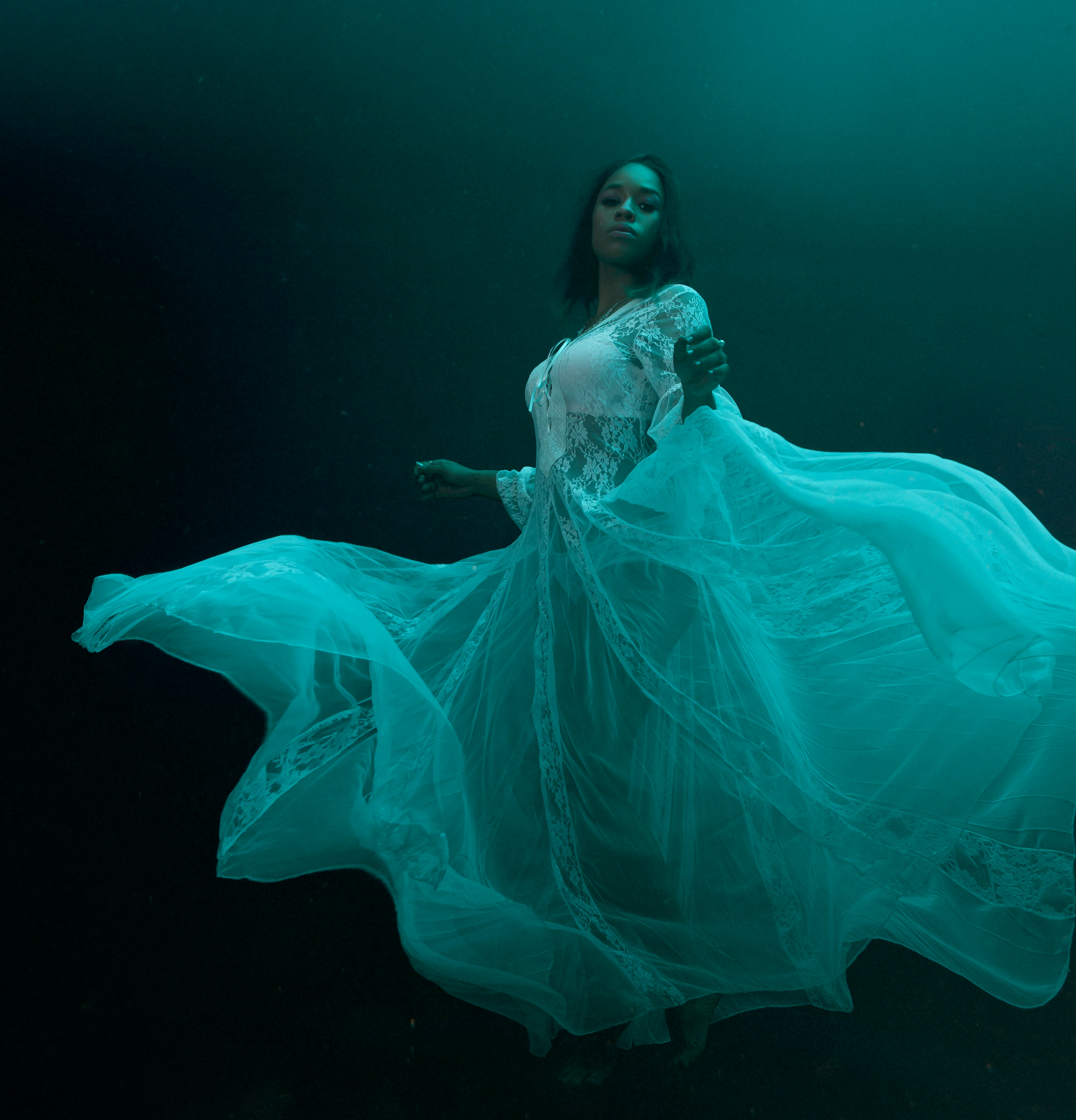 A woman in a wedding dress poses underwater
