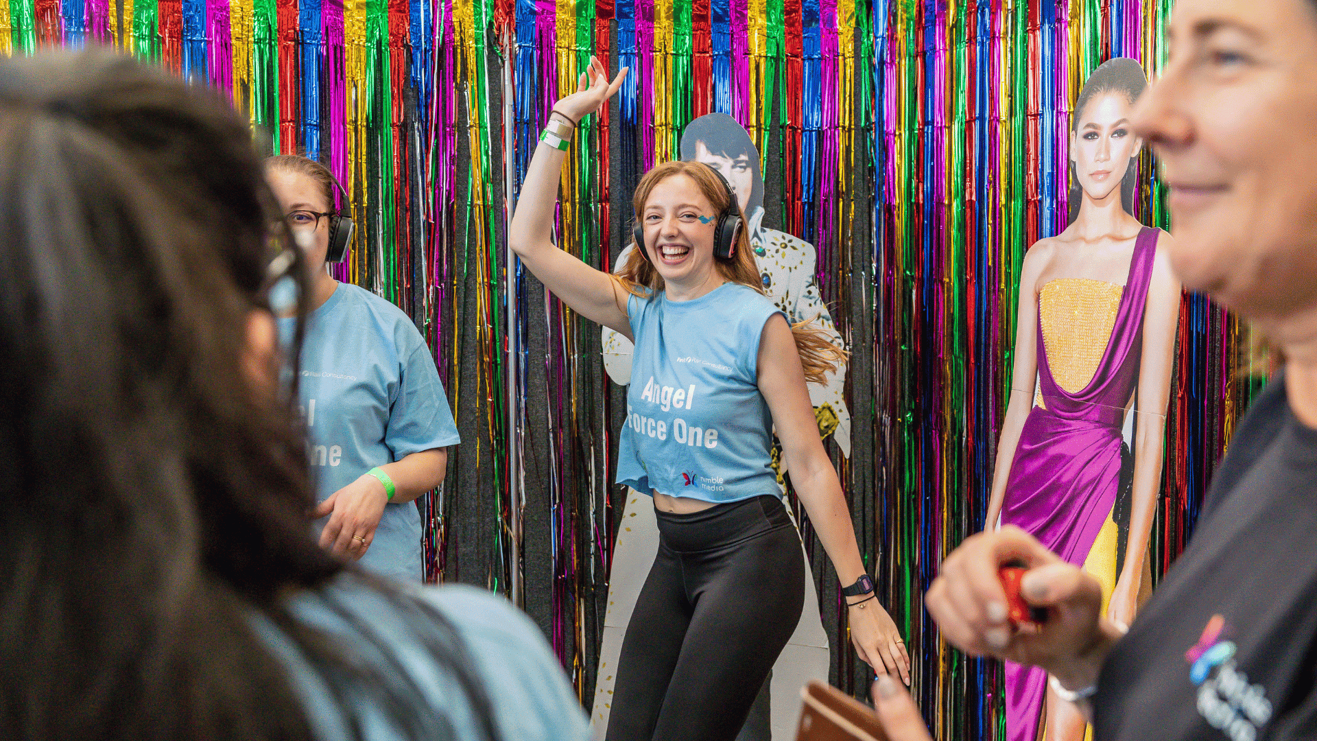 Outdoor team-building event with participants wearing matching blue shirts, taking part in inflatable obstacle courses and games, smiling and cheering, with the words 'ENTER A TEAM' in large bold white and green text across the image.