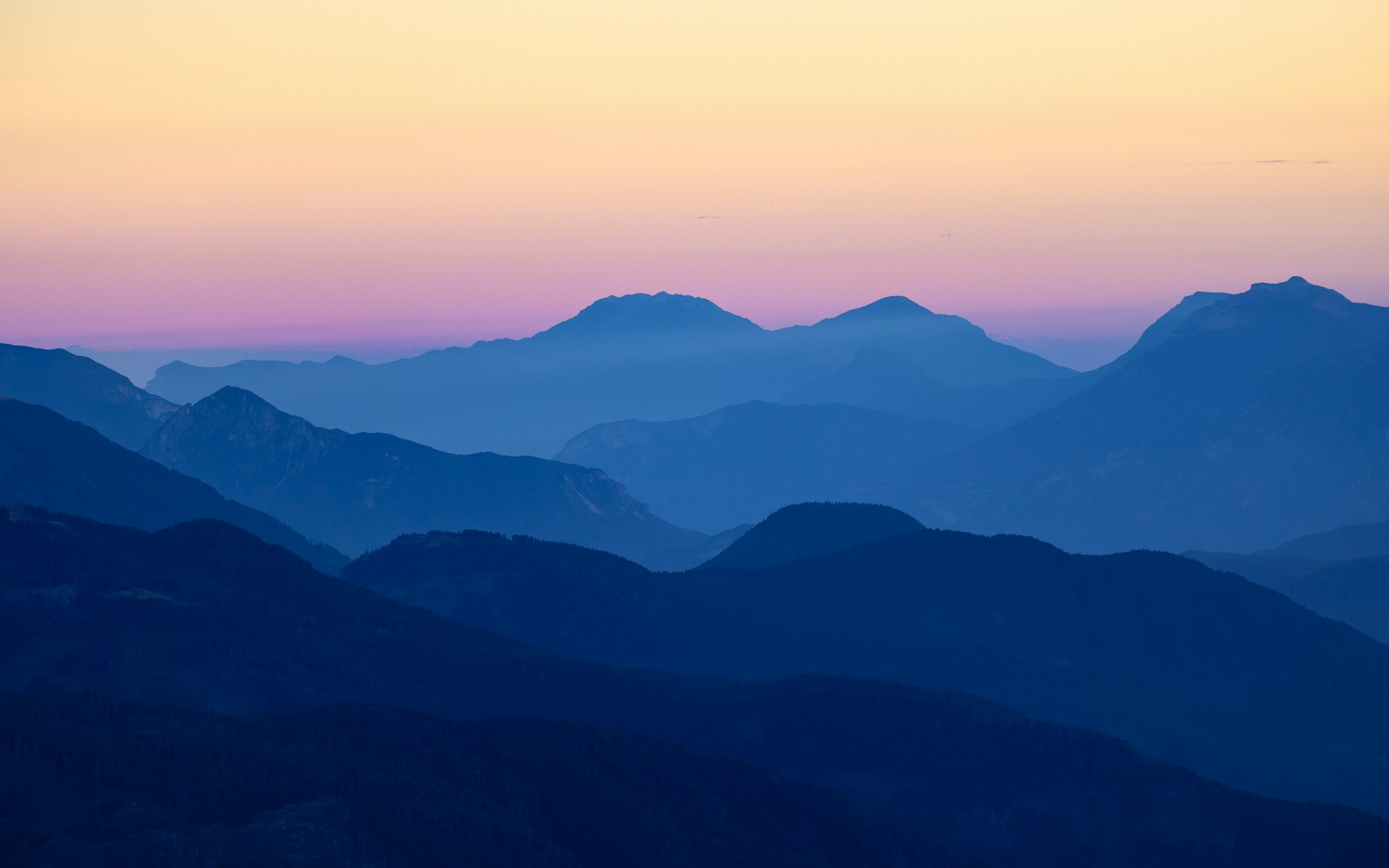 A view of a mountain with a pink sky in the background