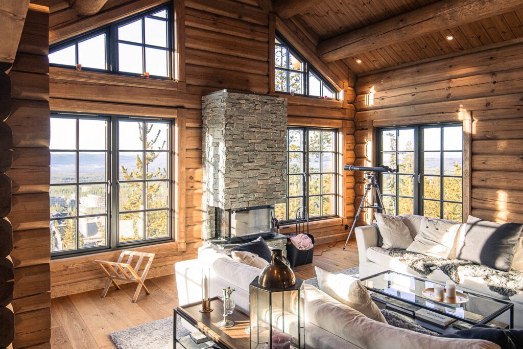 Cozy log cabin interiro with large windows and fireplace.