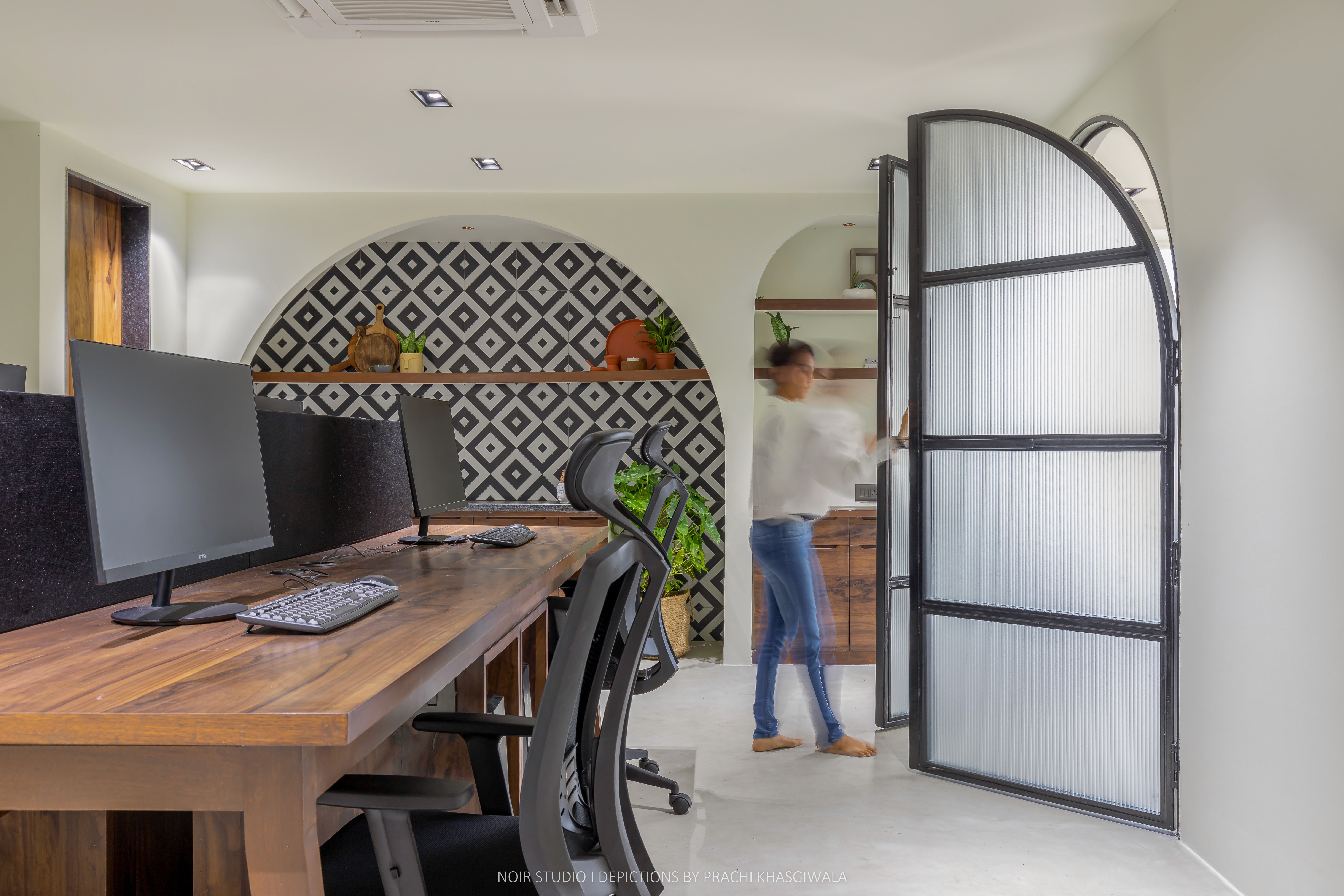 Black and white image of people working at a table with laptops, showing hands gesturing during discussion of digital content displayed on screens, with fabrica® logo in the corner.
