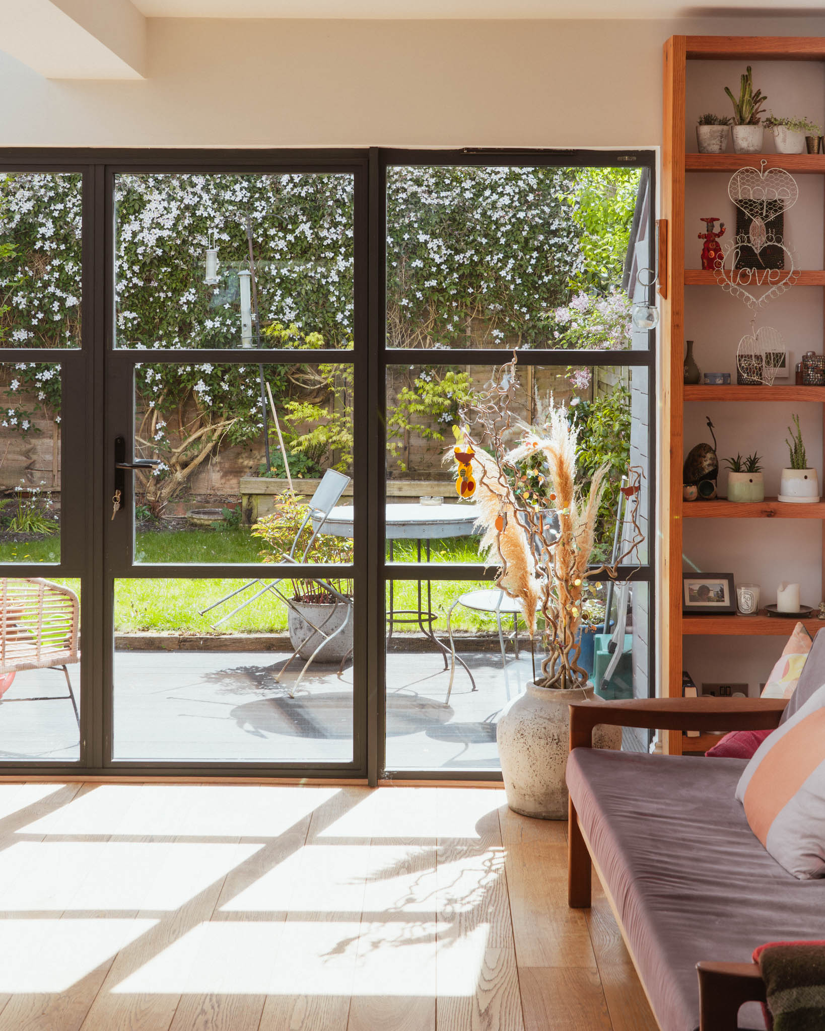 Living room with built-in open shelving, rooflight and garden views through steel-framed glazing, Bristol residential architect