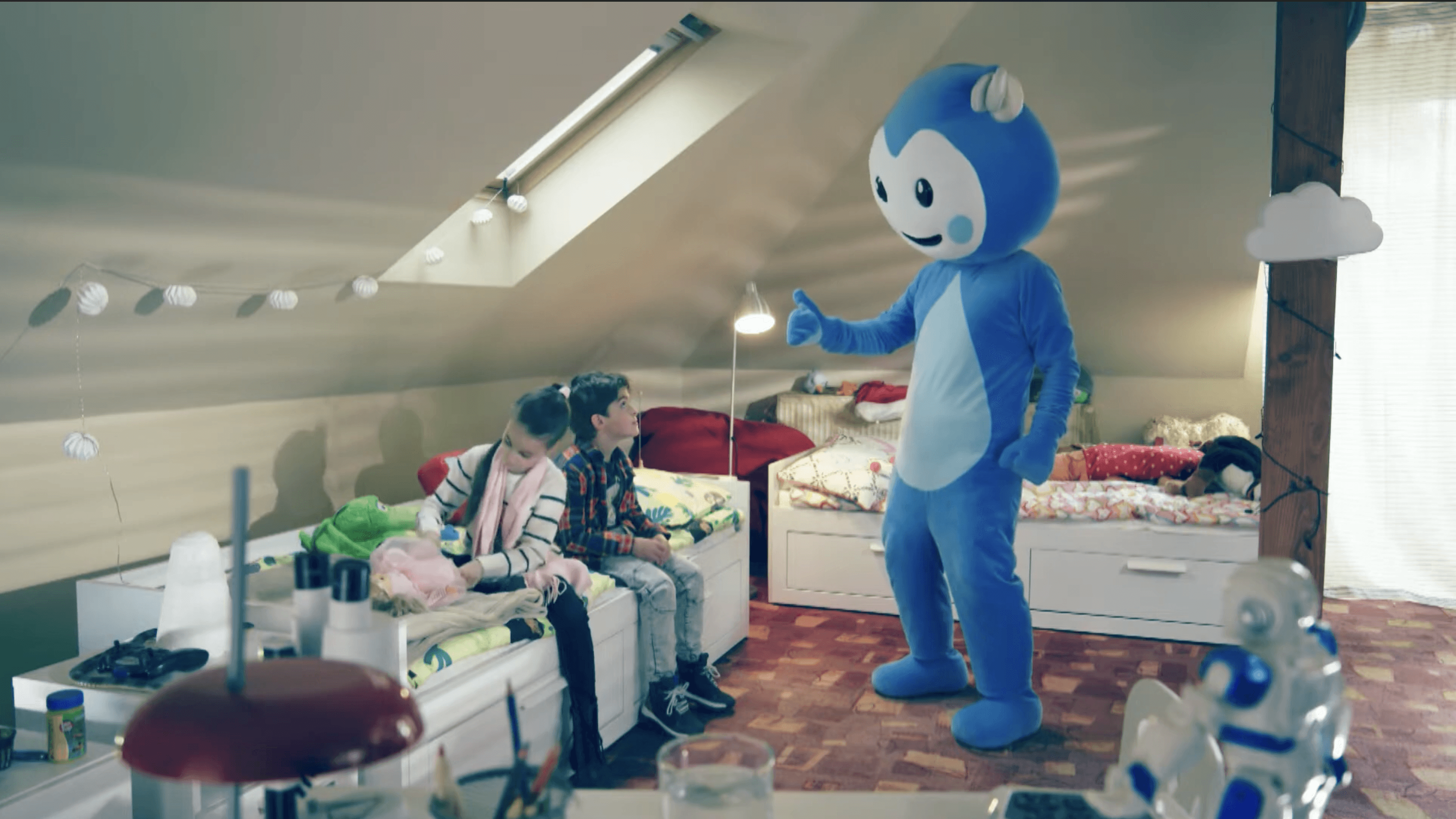 Cseppbarát kék kabalafigurája ruhákat válogat a gyerekekkel a szobájukban