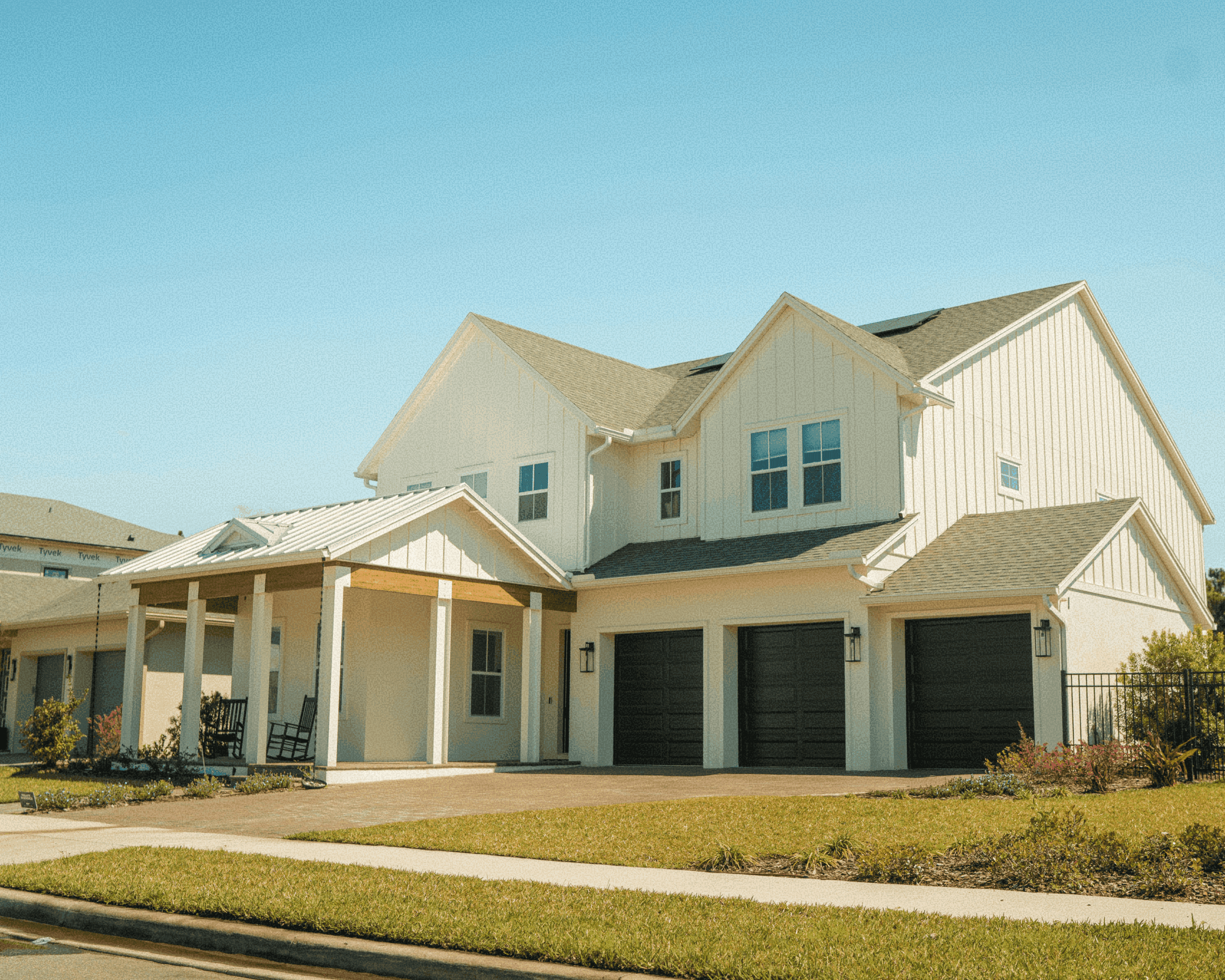 Modern farmhouse style real estate listing featuring a two-story home with white board and batten siding, a metal roof front porch, and a three-car garage with black doors.
