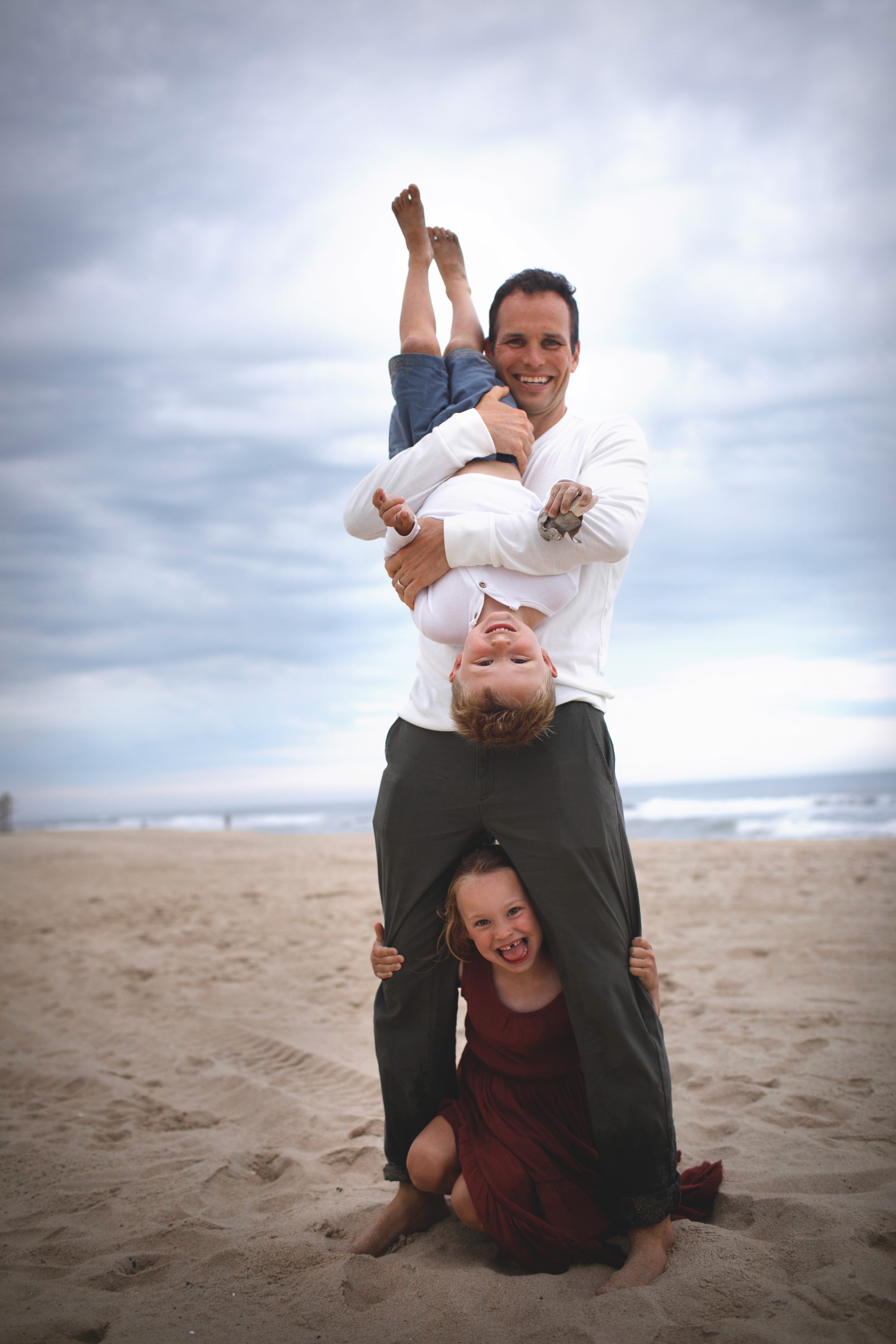 Family playing at the beach with their son lifted high into the air