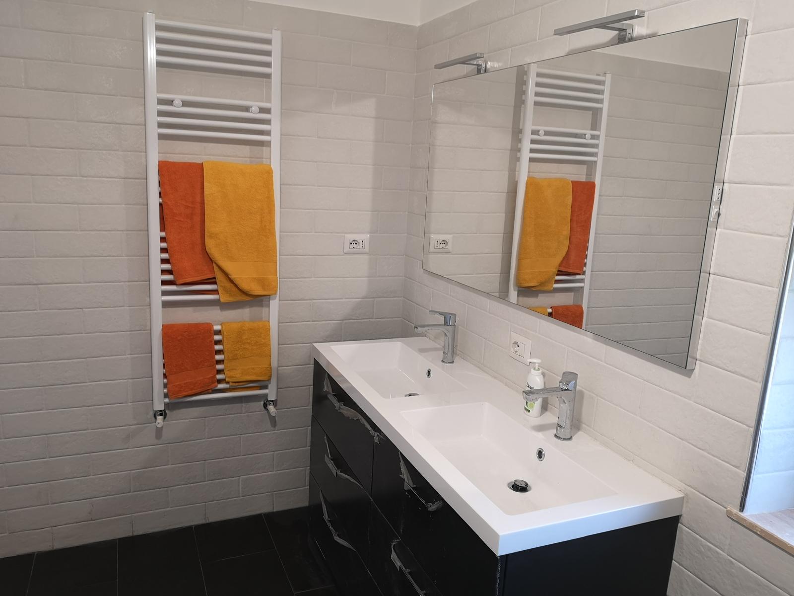 dettaglio di bagno ristrutturato con lavabo doppio e specchiera illuminata