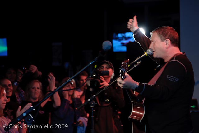 Singing guitarist plays to an audience.