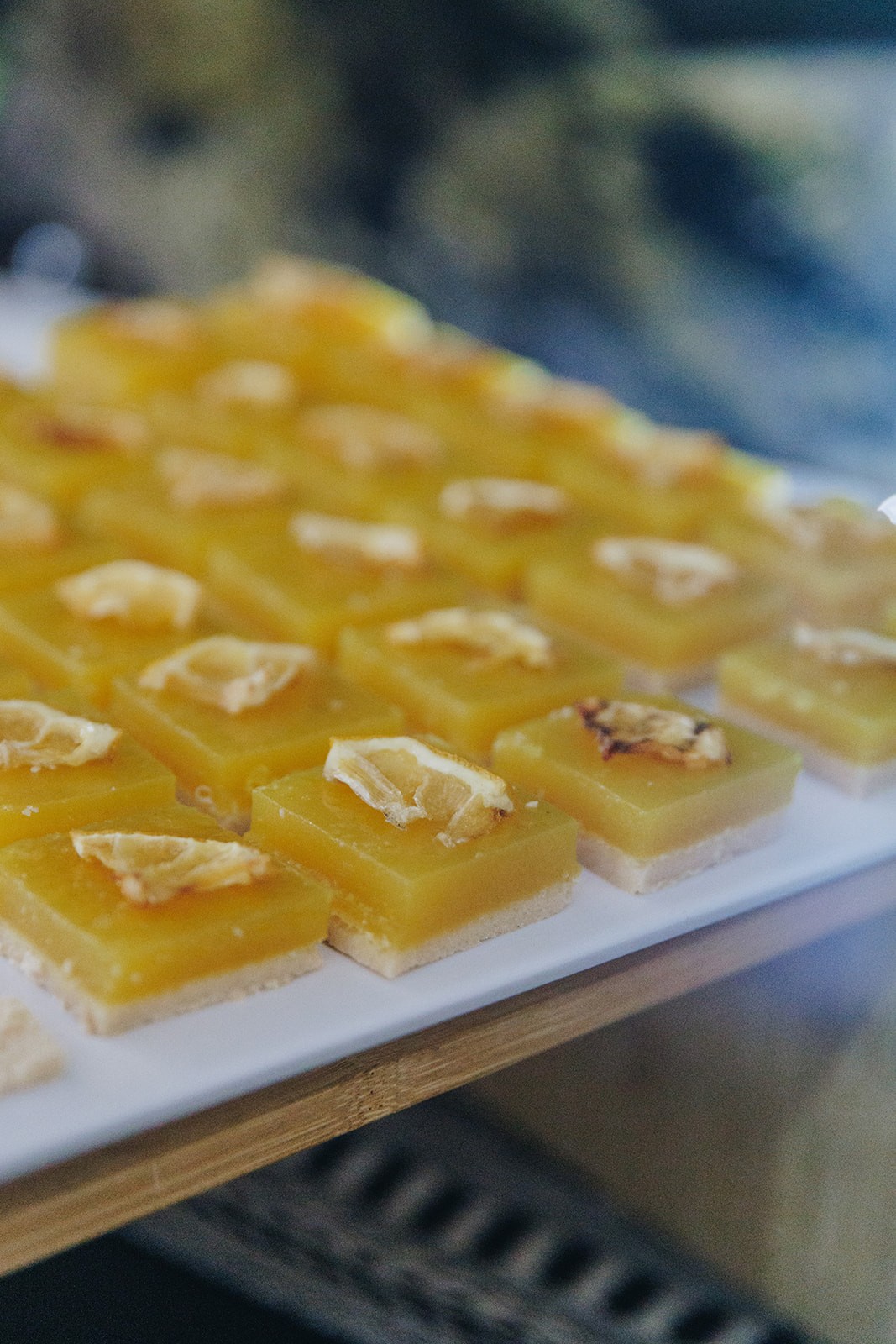 A close-up of a tray of golden, square-shaped sweets, arranged in a grid pattern, ready to be served.