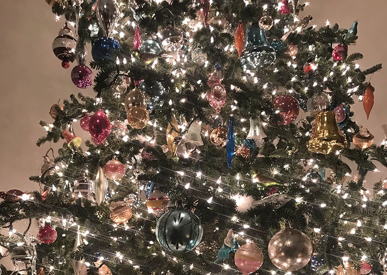 A photo of decorated Christmas tree with bright white lights and colorful globes.