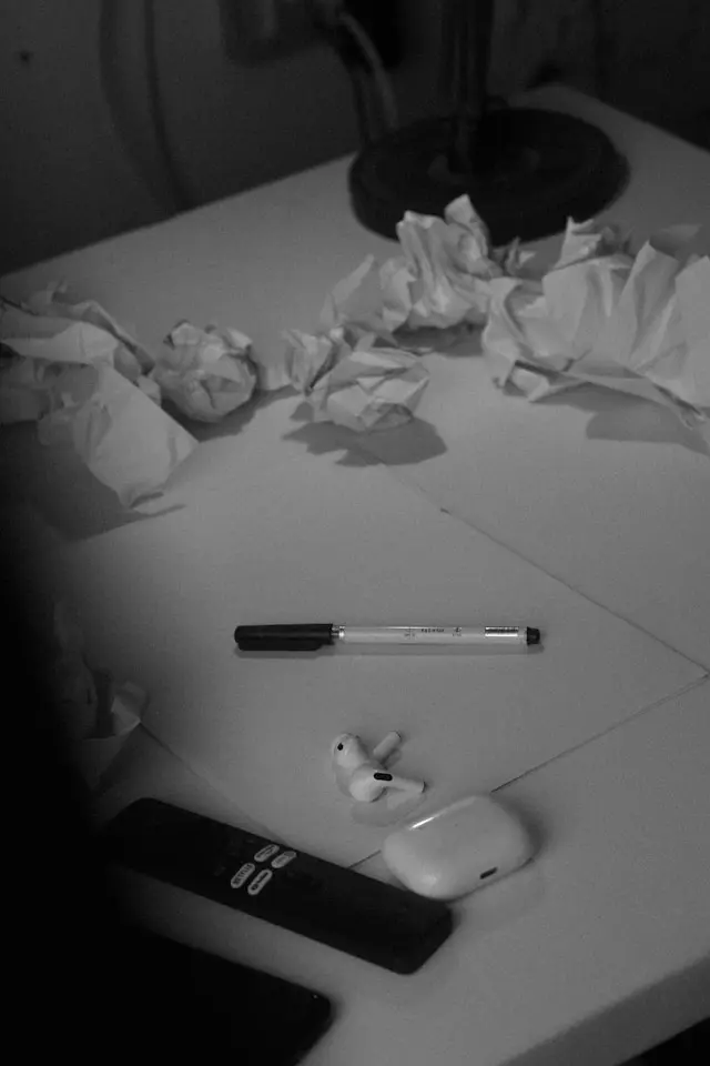 Cluttered tabletop with wadded paper and a pen, suggesting stress and rushed writing