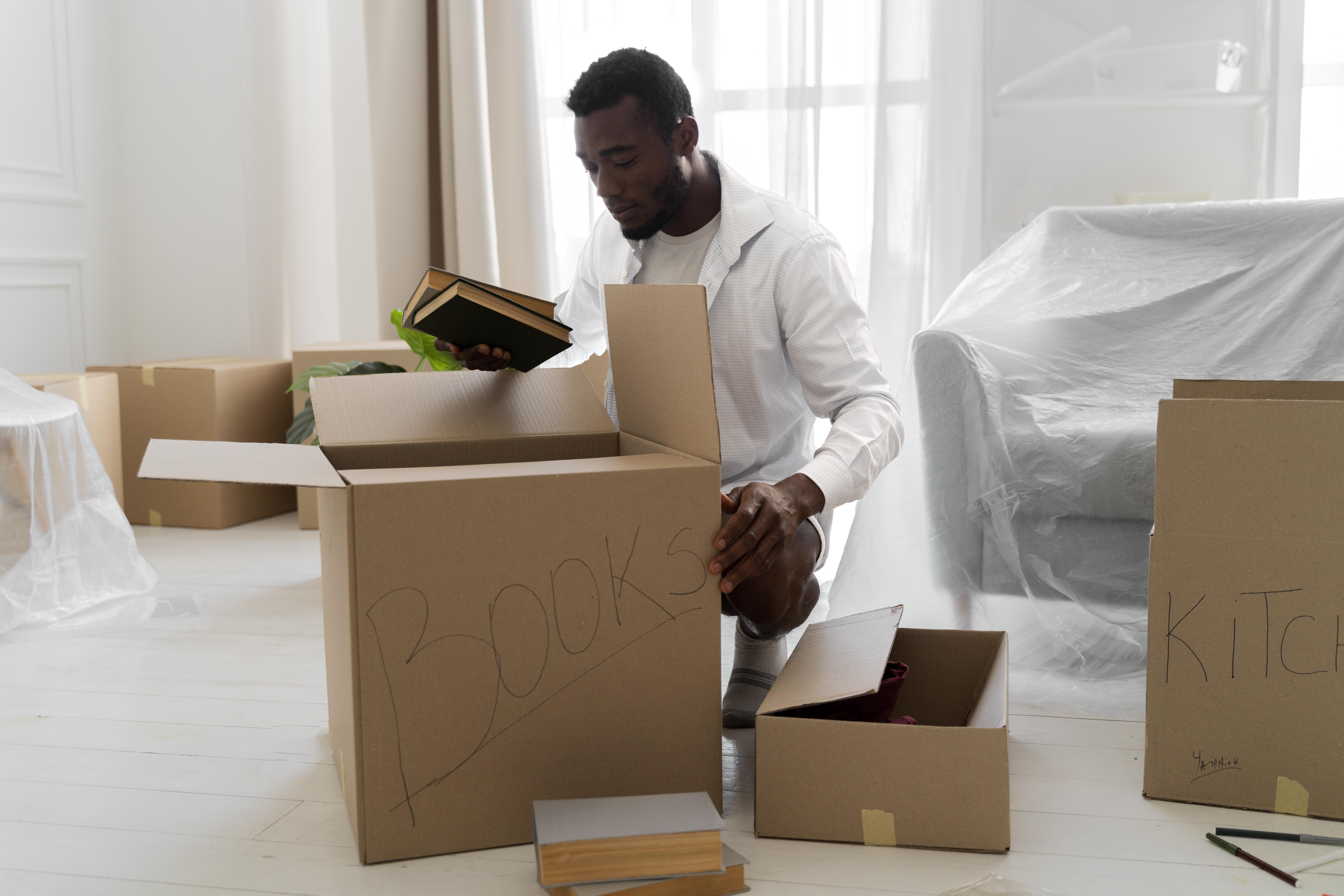 A man packing his things in a well labelled box for a move