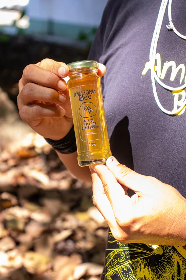 Mãoos segurando uma garrafa de Mel de Jupará.