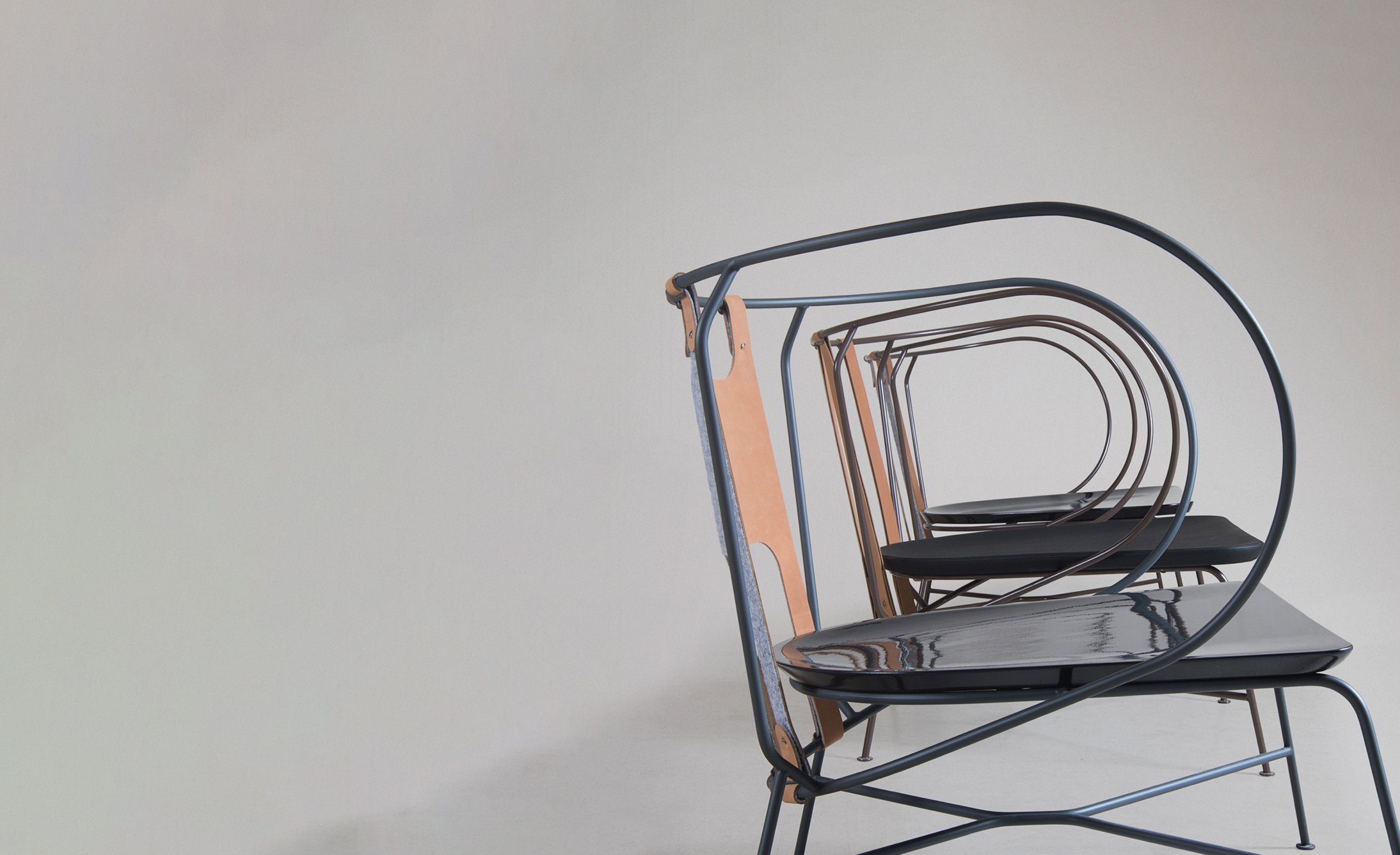 A series of modern chairs displaying a minimalist design with curved metal frames and sleek surfaces, arranged in a line against a neutral background.