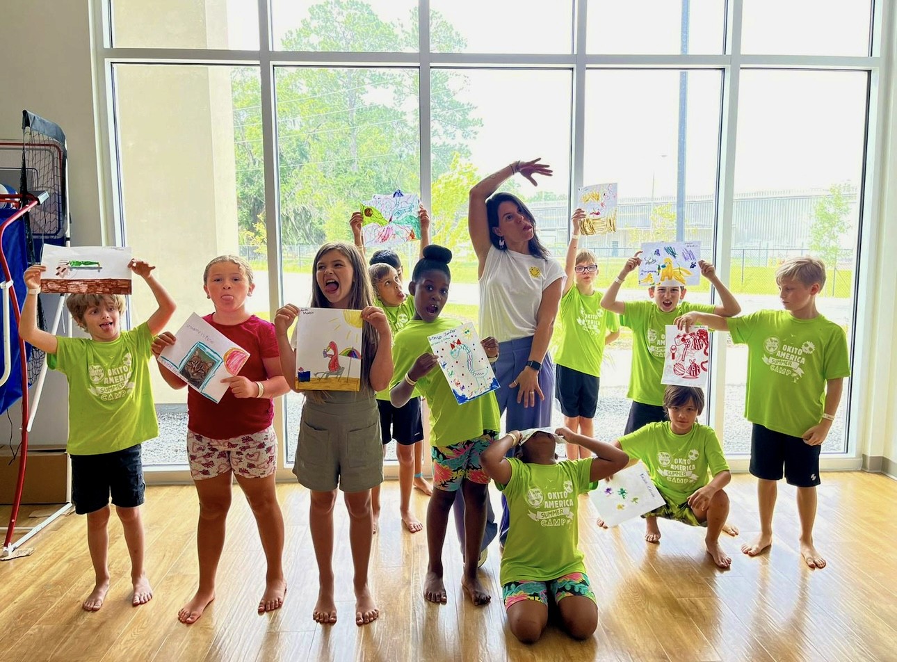 Children holding up artwork and making silly faces.