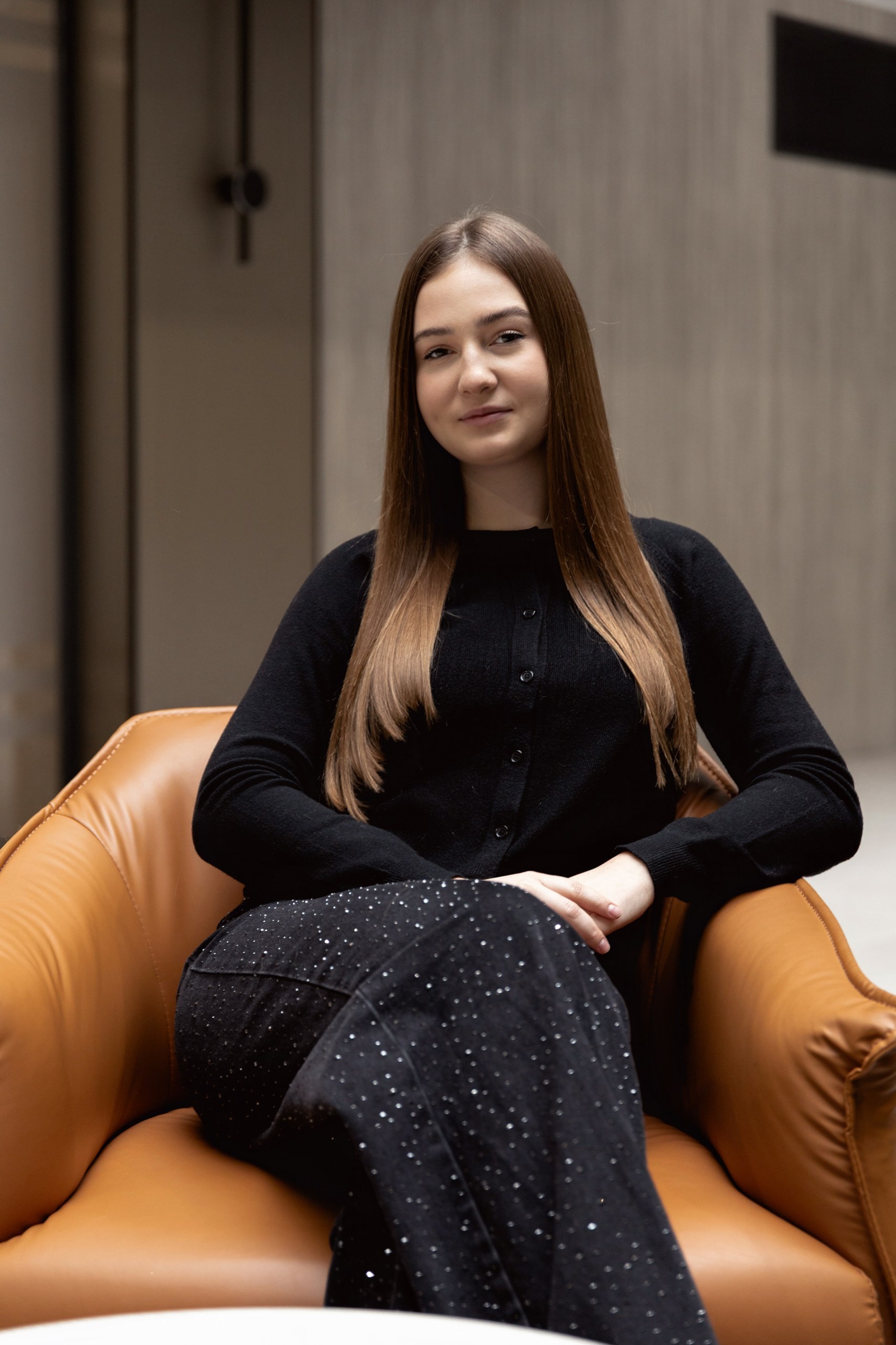 Smiling blonde woman with freckles in a white shirt, arms crossed, minimalist studio portrait.