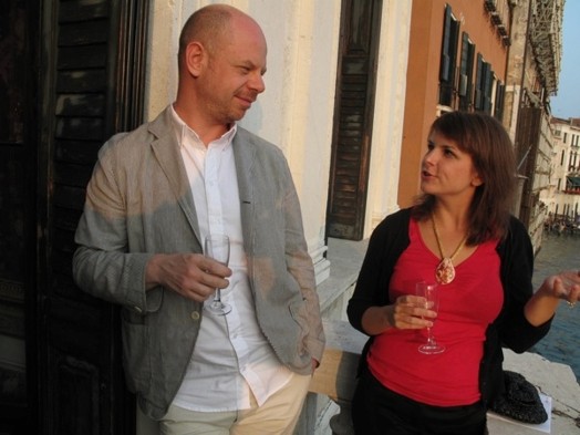 A photo of a man and woman talking to each other while holding vine glasses.