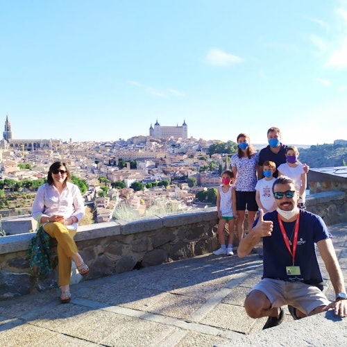 Group of people posing outdoors with a scenic cityscape and historic buildings in the background.