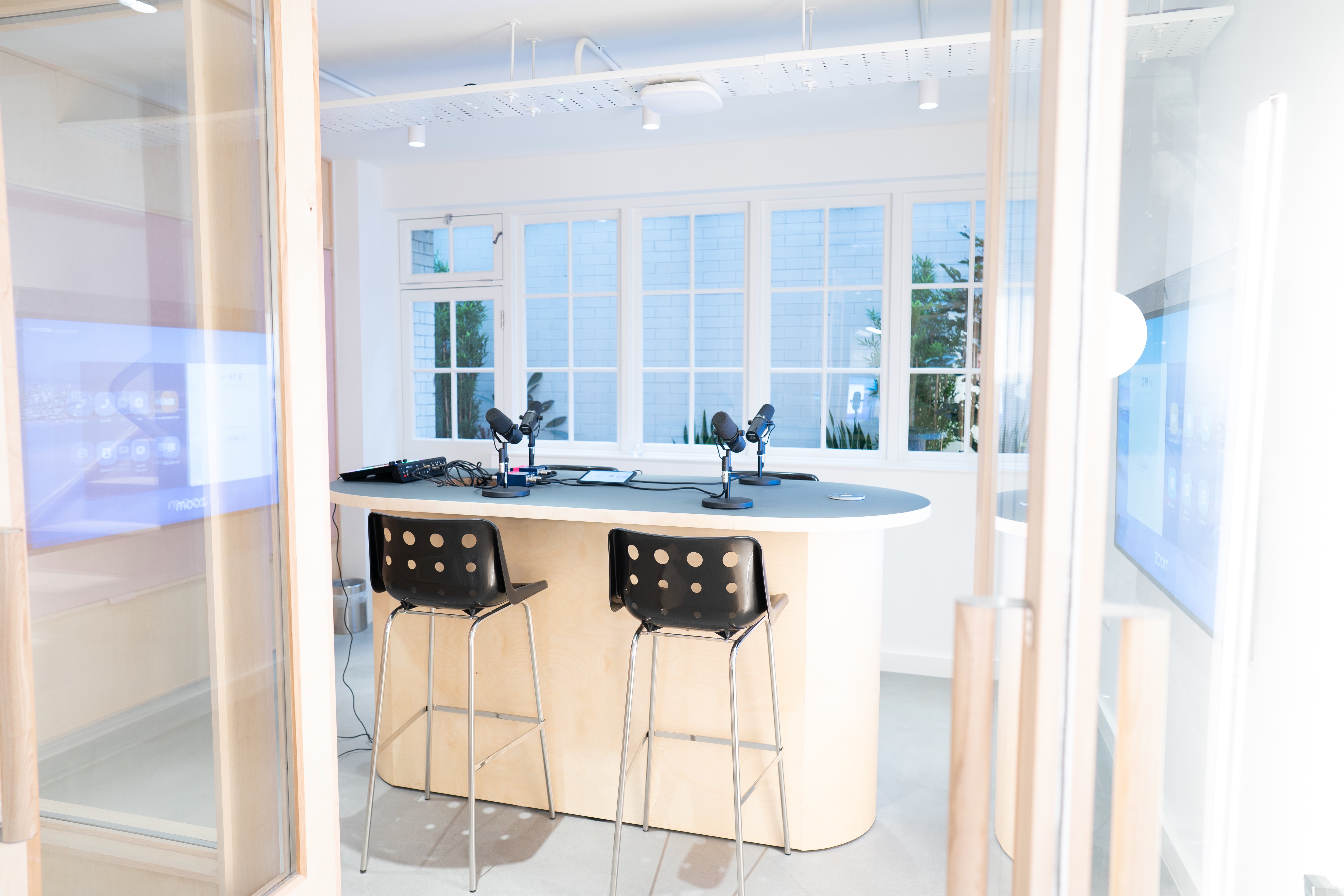 C-Suite-Invitationer and a woman in a light sweater sit at a desk with a laptop, discussing something. The room is dimly lit, creating a focused atmosphere.