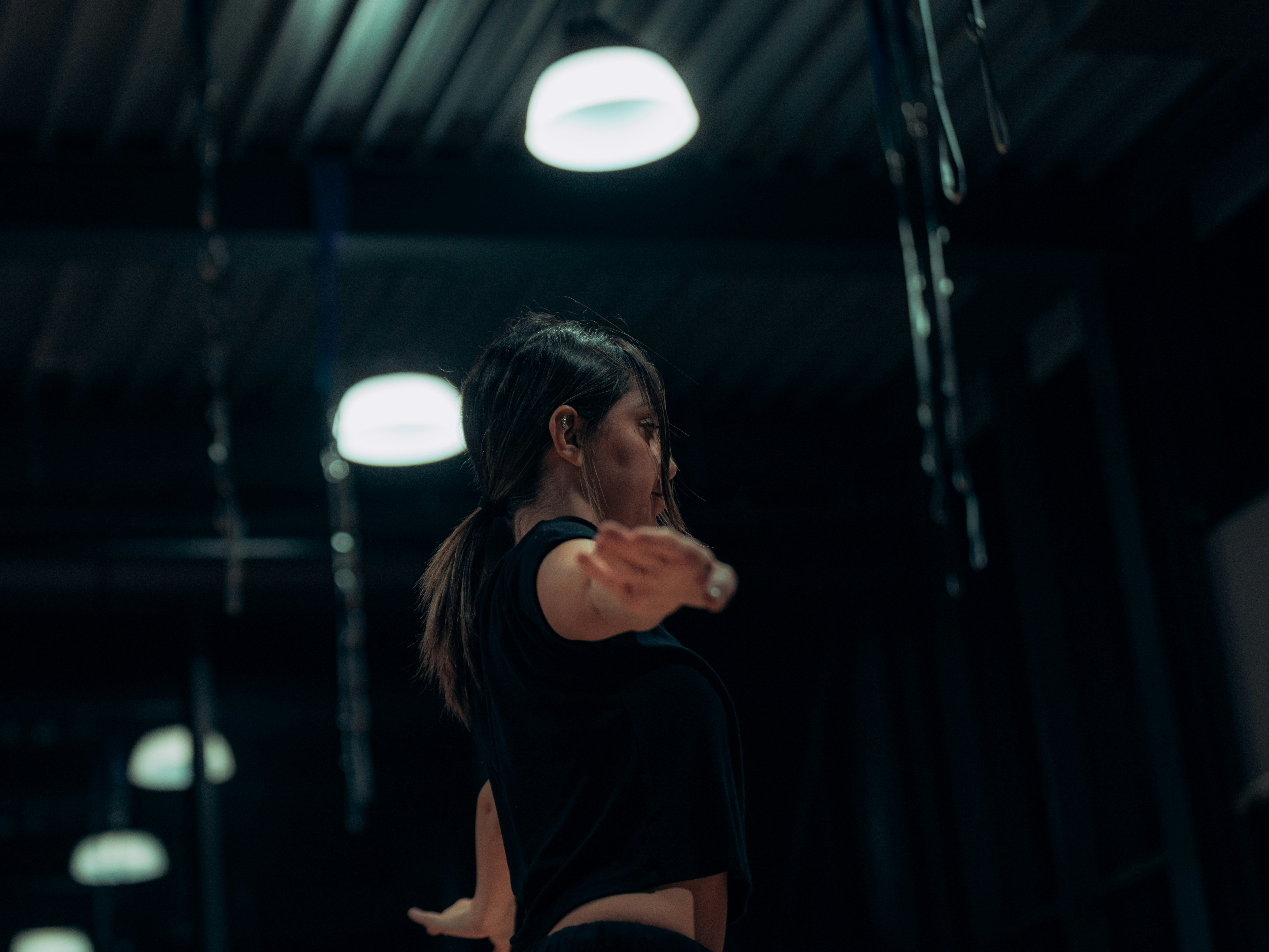 A thrower following through under hanging lights in a dark hall