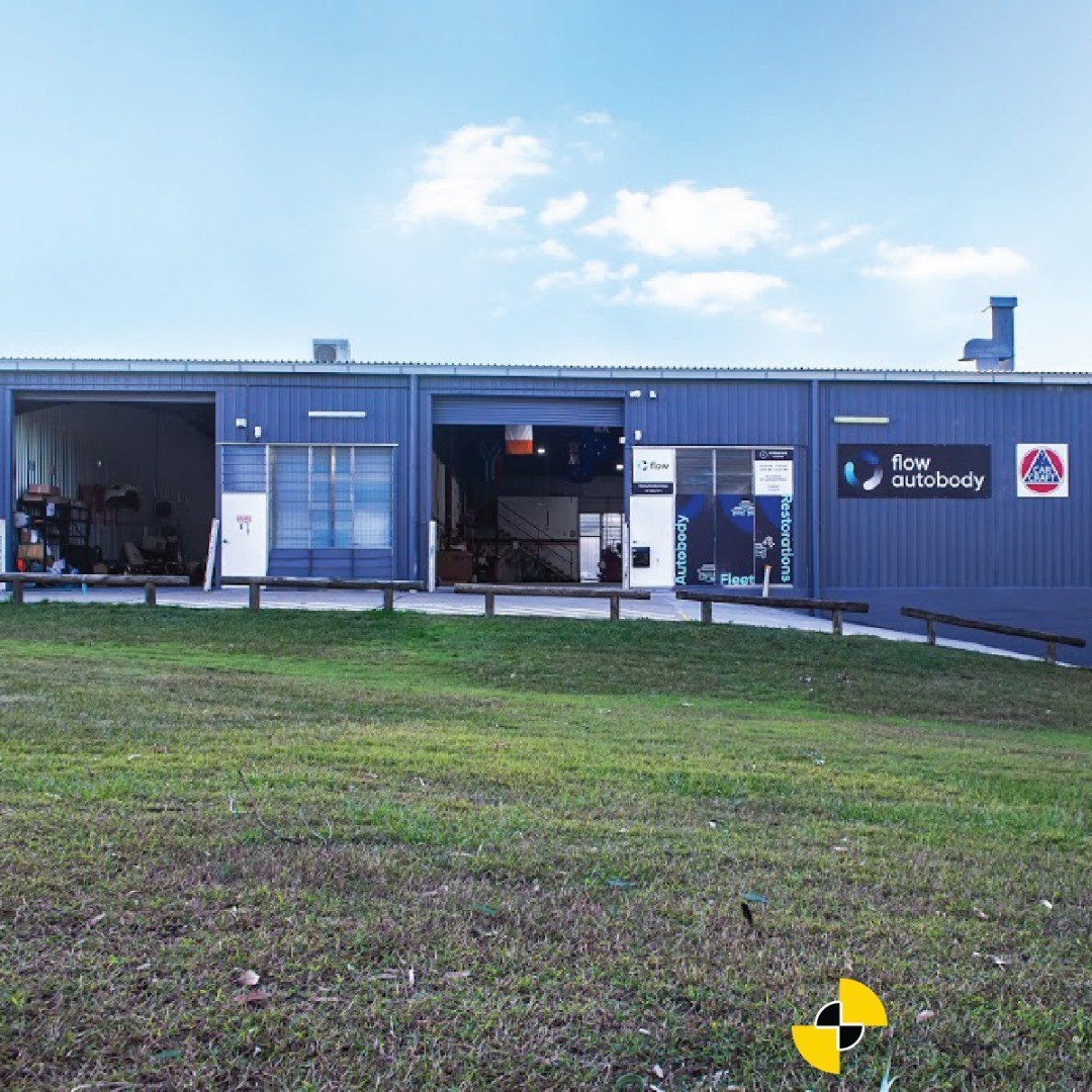Blue autobody shop with open bay doors.