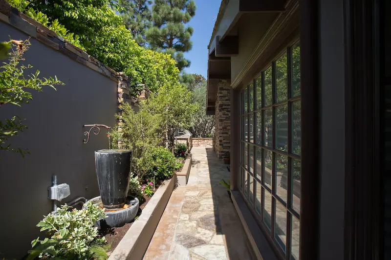 Side hardscape walkway with large wooden windows from the Big Canyon Remodel project. Photo by Chris Darnall.