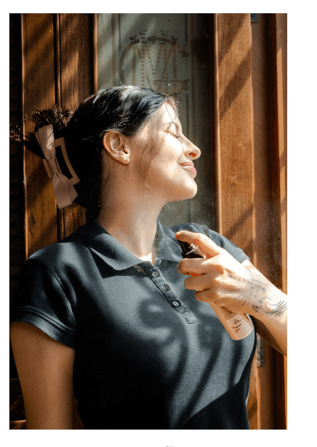 Michelle Espinosa Badias applying facial mist while standing in sunlight at SKNKR BAE! studio.
