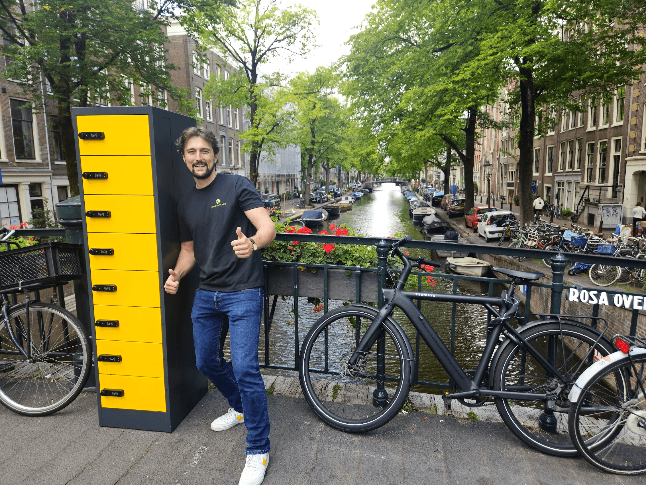 A person placing an e-bike battery into a charging locker, with charging cables connected and a digital display visible on the locker unit.