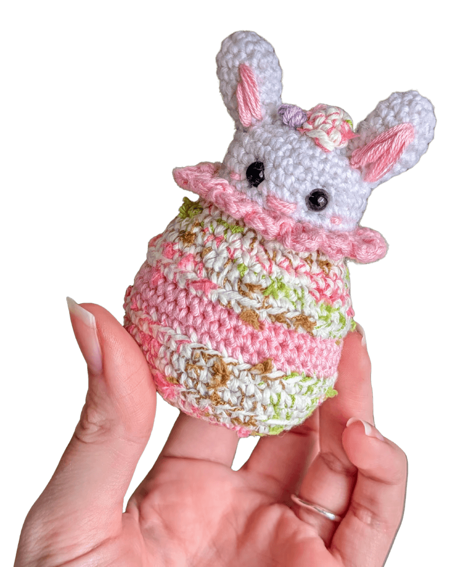 A cute, handcrafted plush hedgehog toy with brown yarn spikes and large, friendly eyes sits facing forward on a white background.