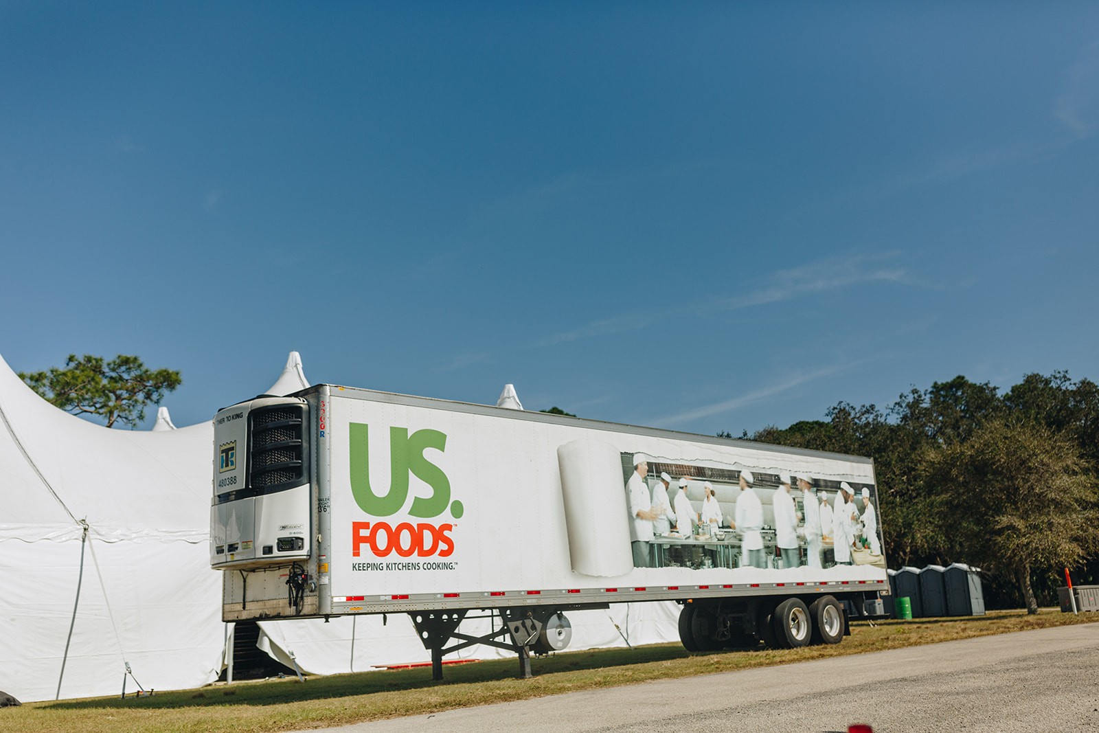 A large truck with the logo "U.S. Foods" parked outdoors under a clear blue sky.