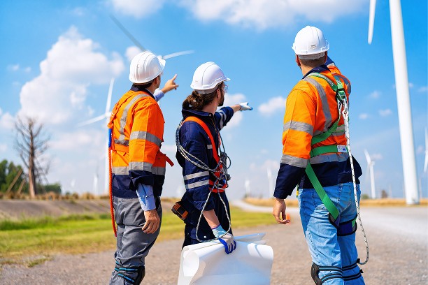 A talent recruiter with a soft smile working on her laptop in the office. The angle is on her face so we can't see what's is on the screen. She is wearing a blazer 