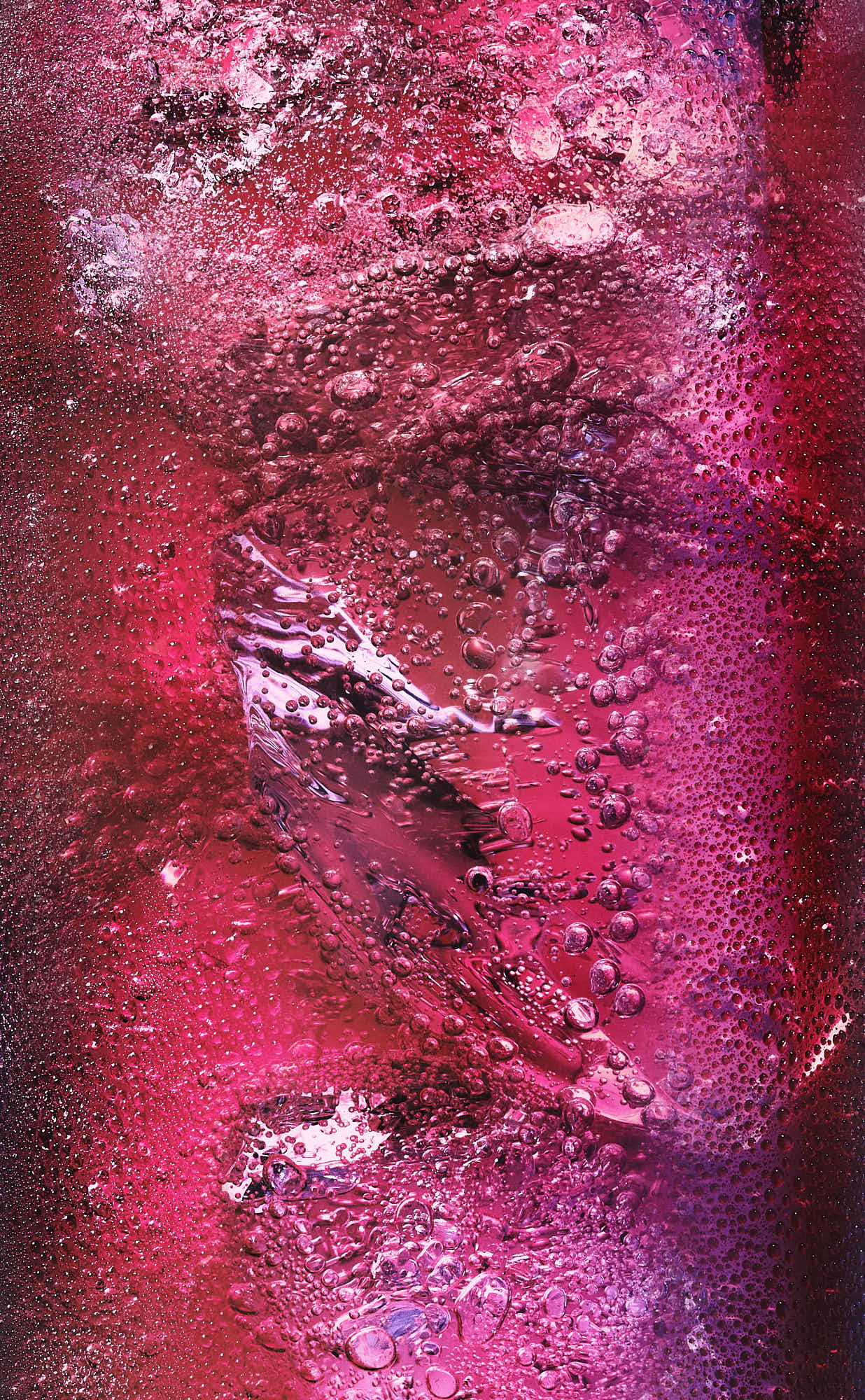 Abstract macro featuring vibrant shades of pink and red cocktail with bubble.