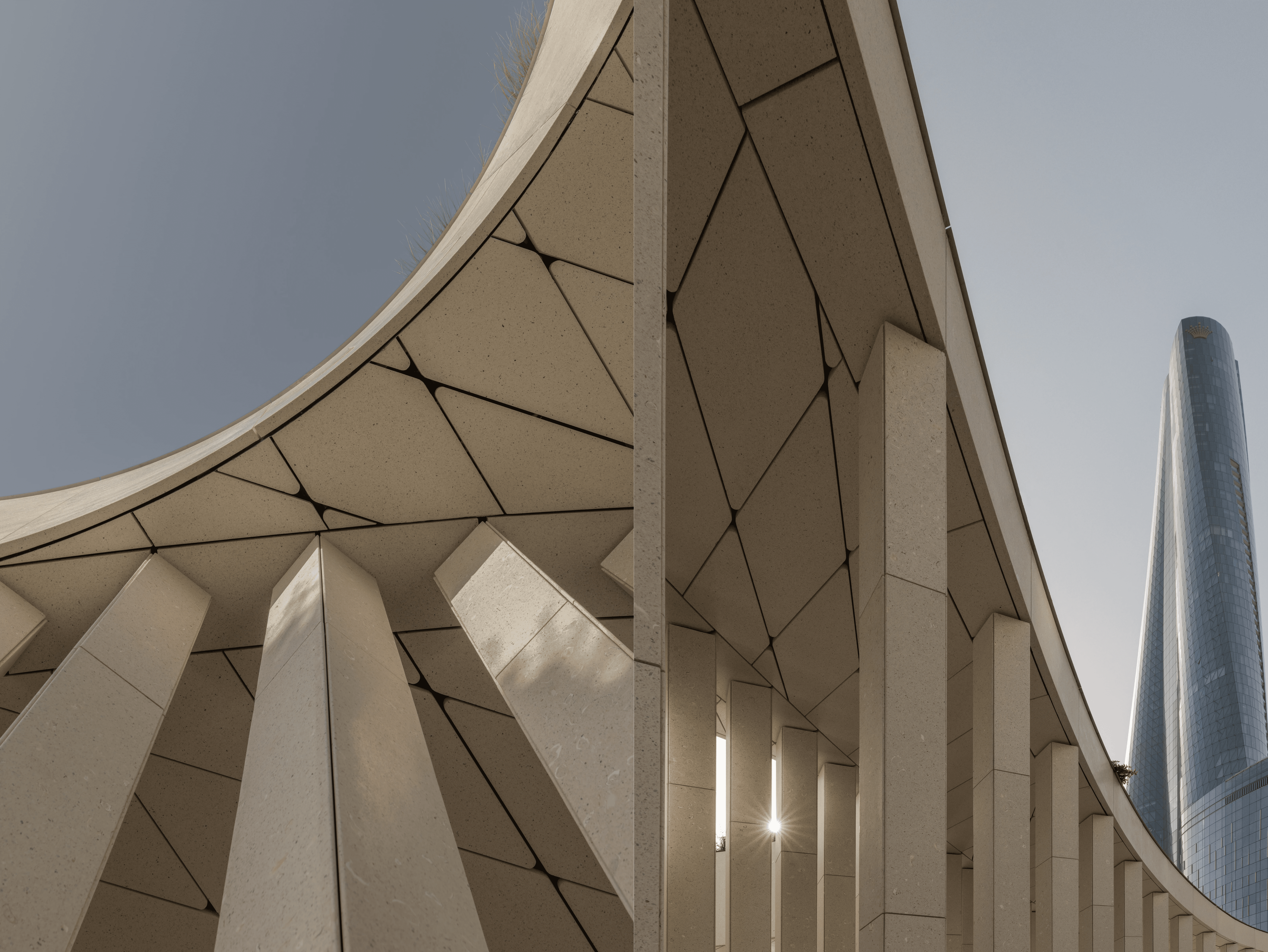 Photographed from below, the pavilion's curving roofline and rhythmic colonnade dissolve into an abstract study of geometry, revealing how shifting perspectives transform a minimal structure into a dynamic spatial experience.