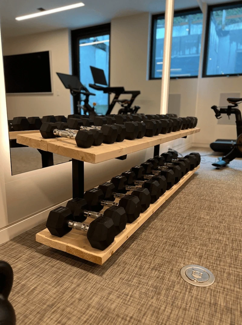 Custom home gym in a Calgary residence featuring a tiered dumbbell rack, mirrored wall, and dedicated strength training area with clean, modern finishes