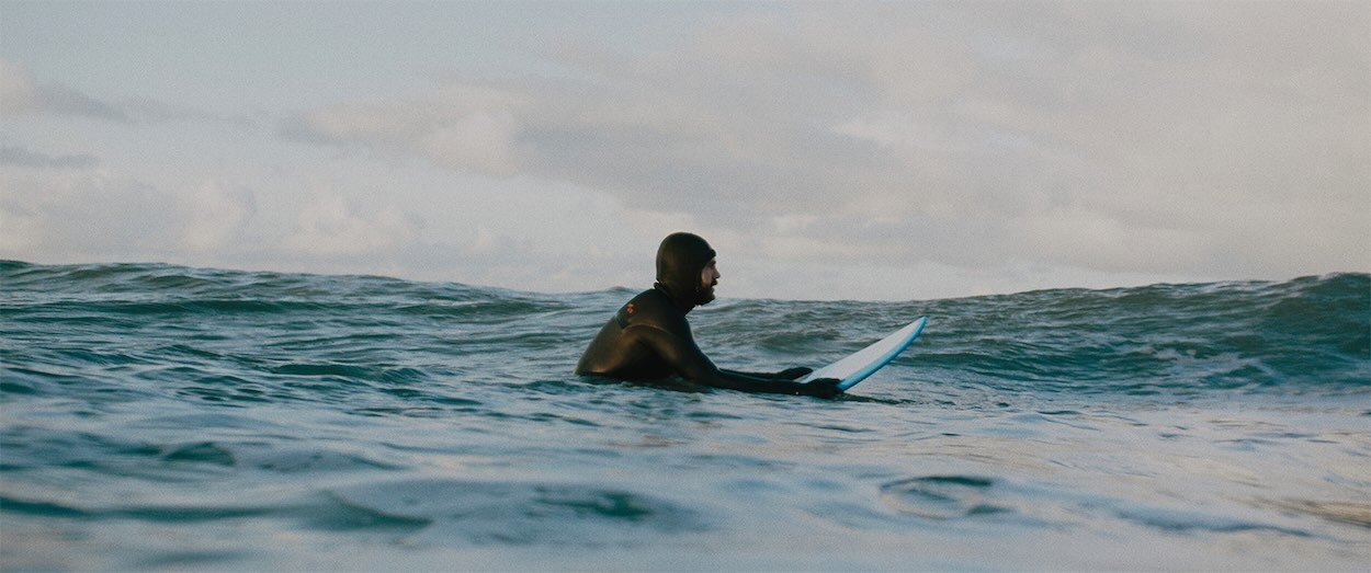 Man sitting in ocean on a surfboard wearing a wetsuit