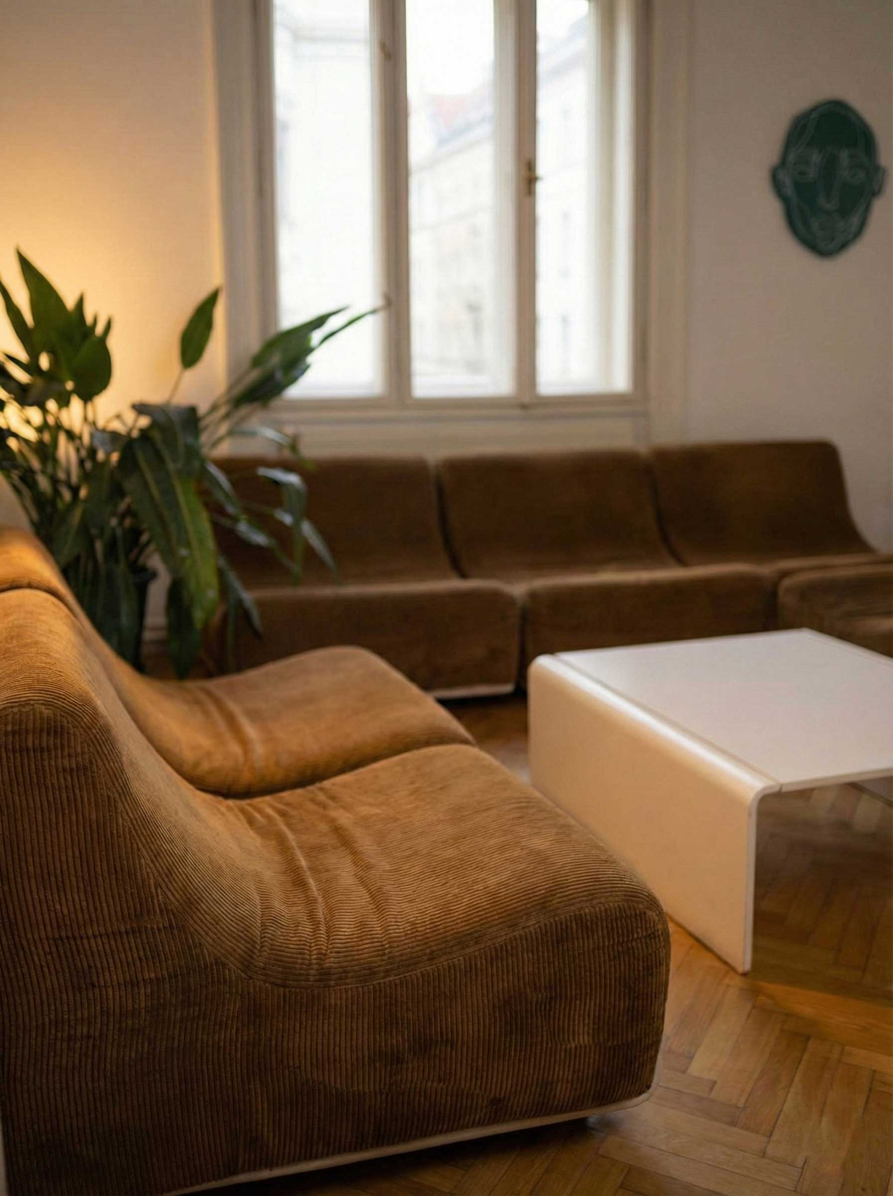 Modern red brick apartment or office building viewed from below against a blue sky, showcasing its geometric architecture with evenly spaced windows and balconies.