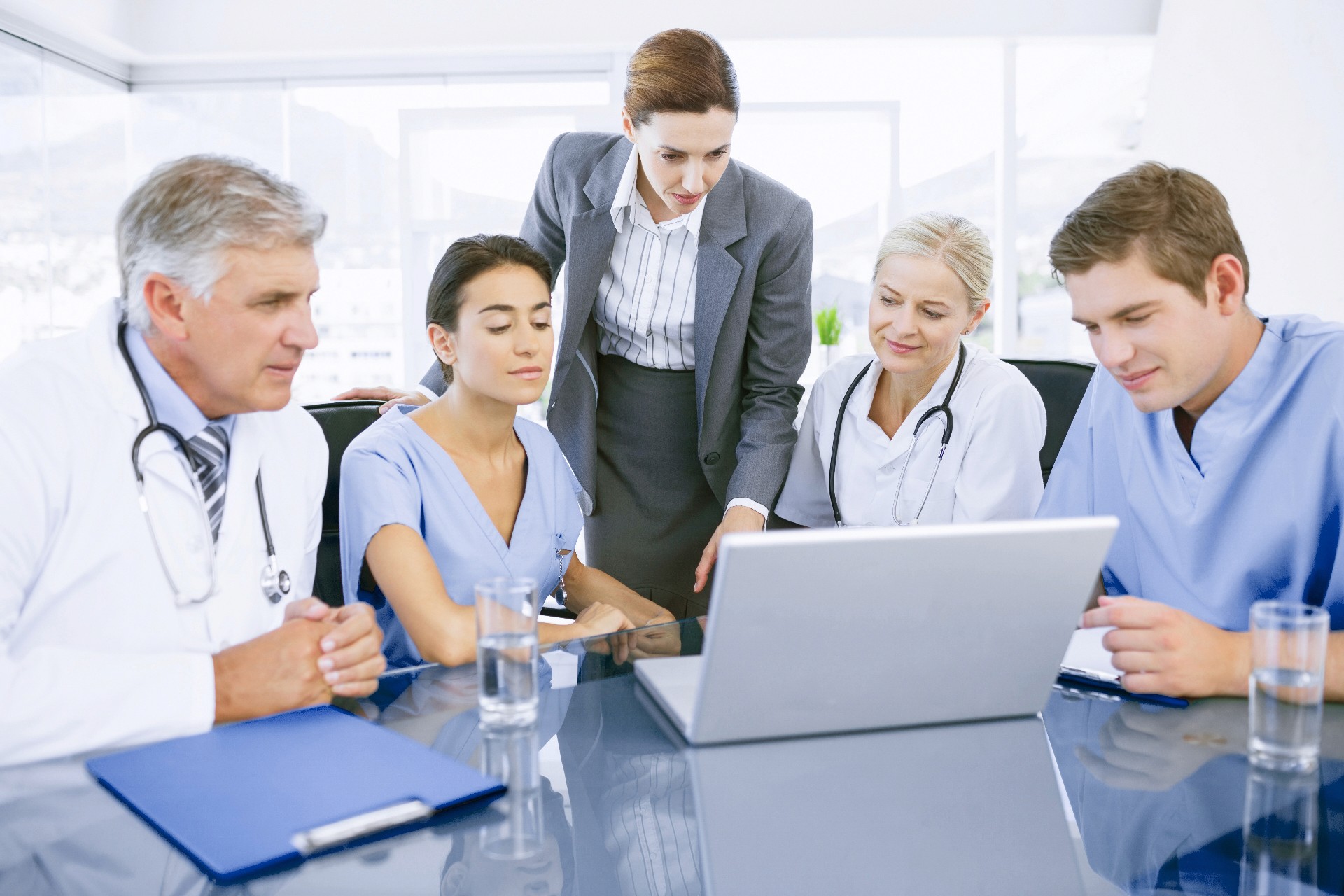 Five professionals, including doctors and a scientists, are engaged in a collaborative meeting.