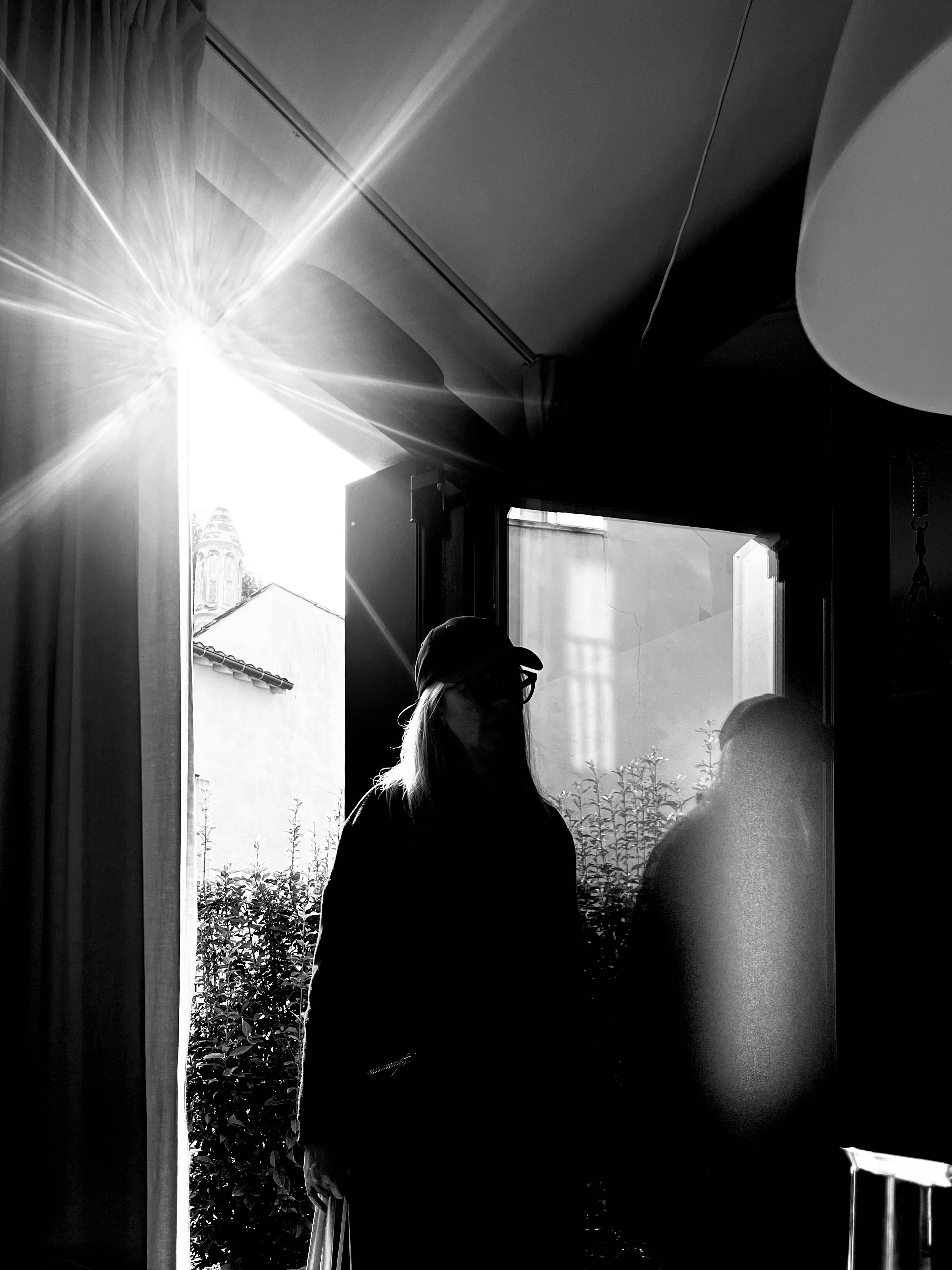 A ray of light illuminates a silhouette of a person standing on the step of a door.