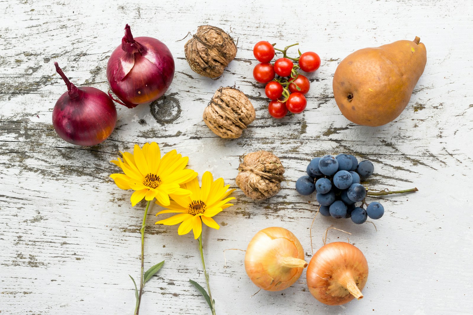 Assorted vegetables, fruit, and walnuts on a white surface, illustrating whole foods that can influence inflammation and gut health