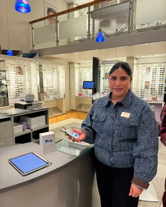 Una óptica enseña la Lupa Inteligente en su tienda, con la caja de LUP sobre el mostrador