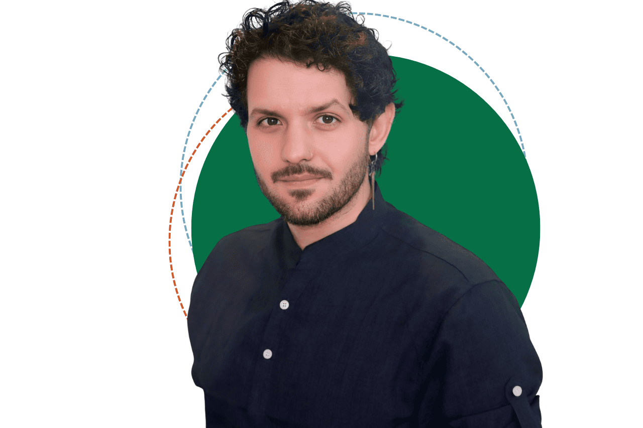 Léo Formigon, homem de cabelo castanho cacheado, médio volume e na altura do pescoço, barba leve, utilizando uma camiseta preta, sorrindo e posicionado de frente para a câmera, levemente inclinado para a esquerda da tela.