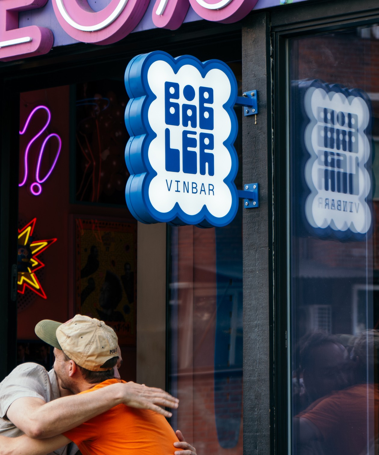 Blue and bubbly custom wall sign designed for Båbler wine bar hanging above happy bar guests.