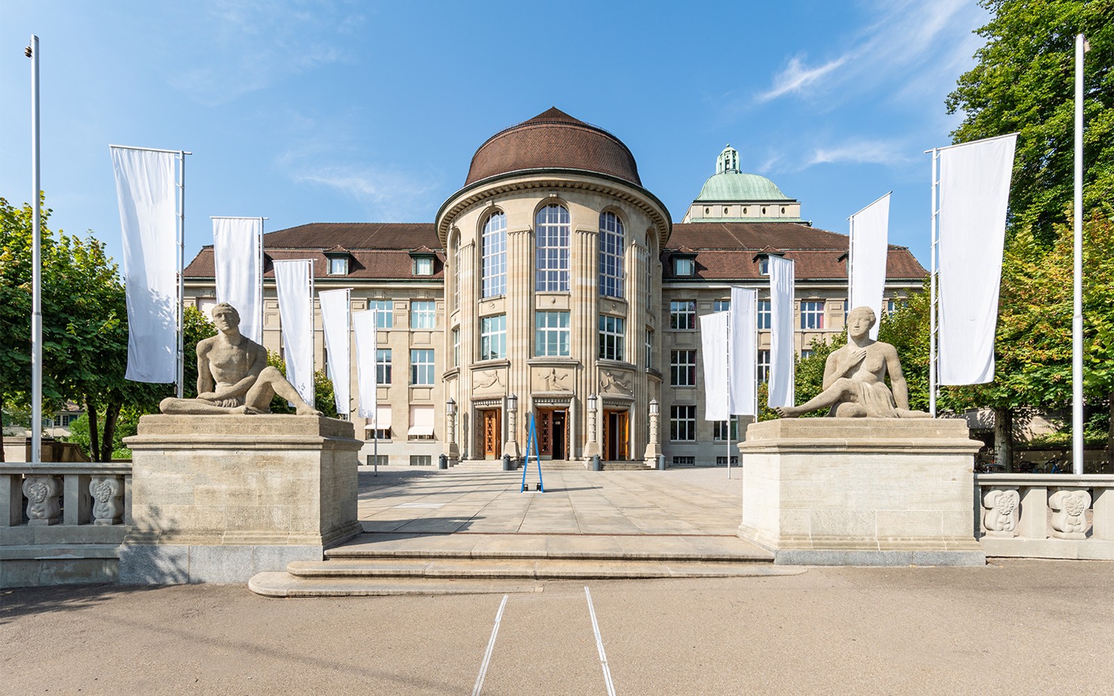 Huvudbyggnaden vid Zürichs universitet med statyer och flaggor på den bästa av Zürichs stadstur.