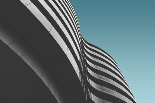 Abstract view of a modern building with wavy, layered exterior against a clear blue sky.