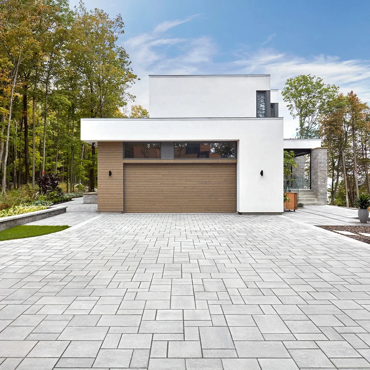 Light gray rectangular pavers across the driveway of a white modern house with a wood garage door.