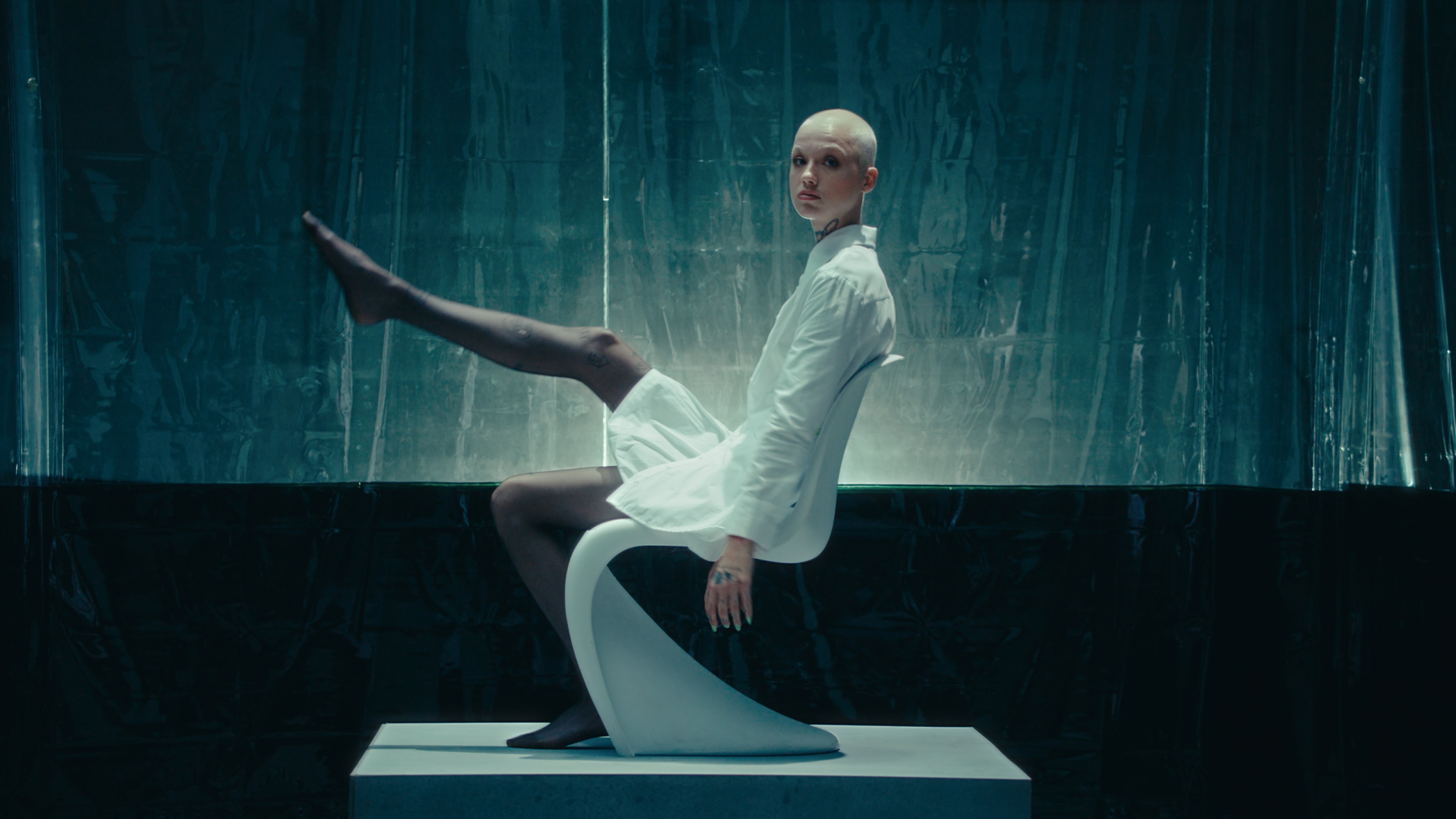 Moody composition from a Sheertex tights commercial, sheer texture lit against a dark teal reflective backdrop