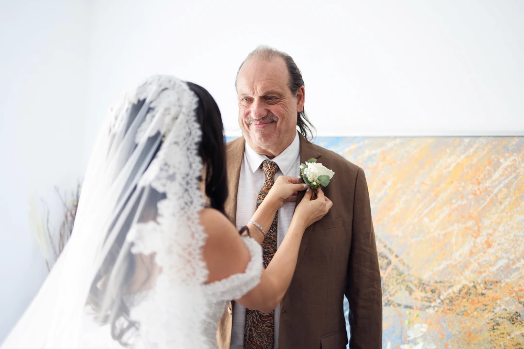 Bride putting a boutonnière on her father's suit