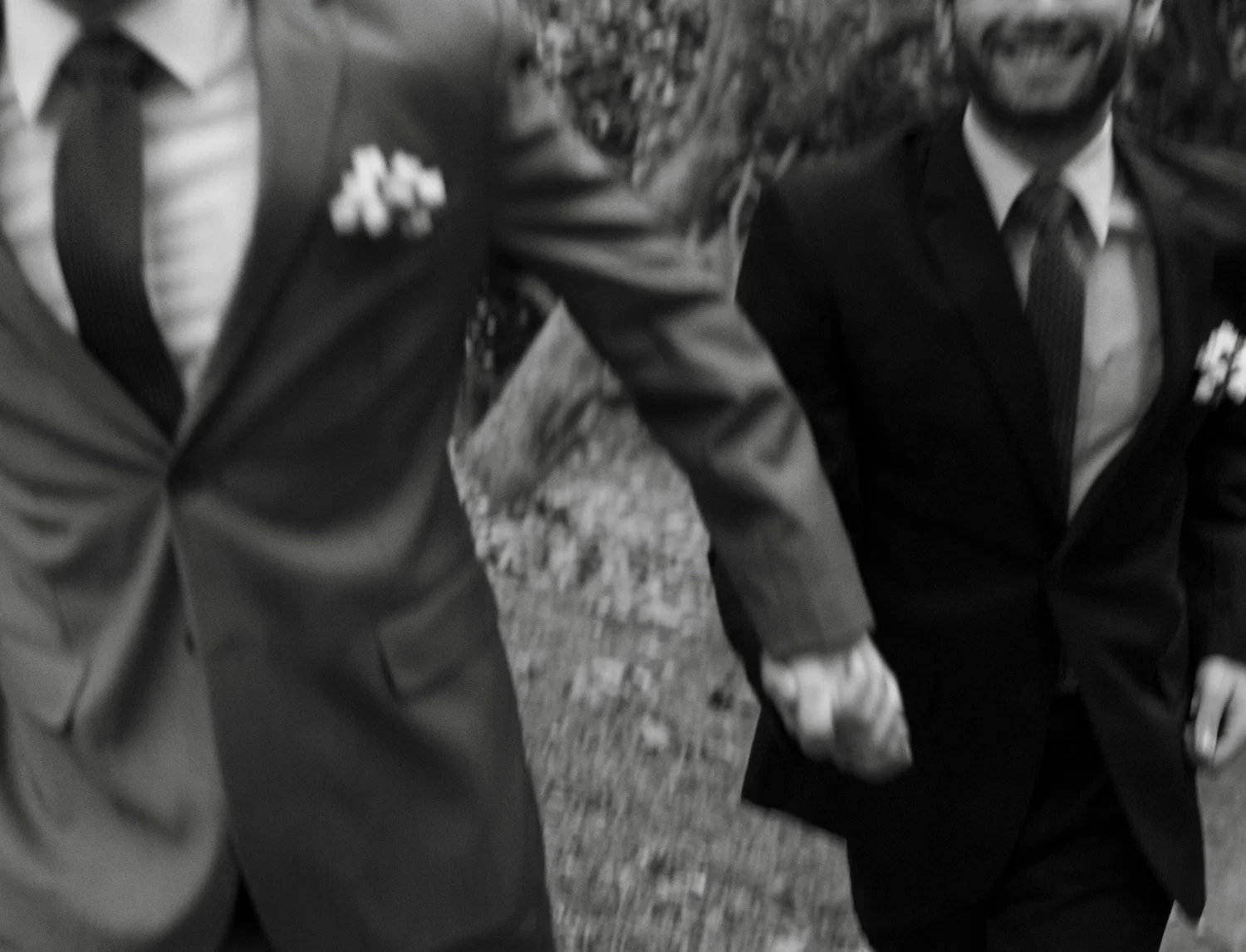 Two men in suits holding hands and smiling, symbolizing love, support, and gay-affirmative therapy for LGBTQ+ couples.