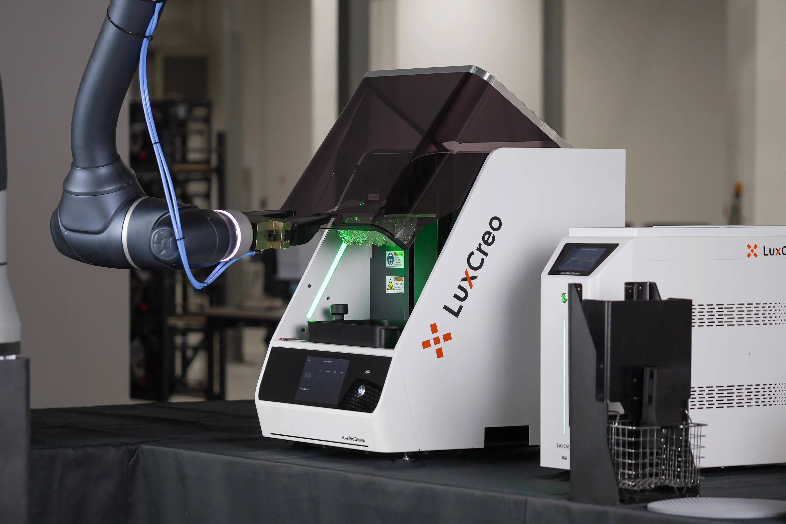 Robot arm harvesting a build platform with fresh 3D printed aligners from the LuxCreo iLux Pro Dental printer.