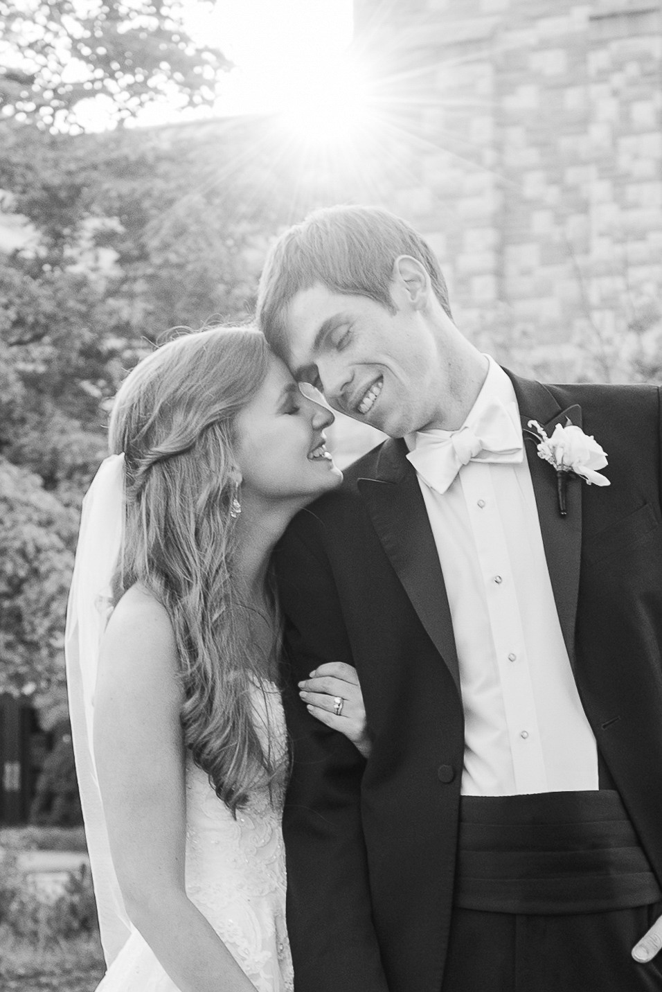 Black and white image of bride and groom leaning into eachother.