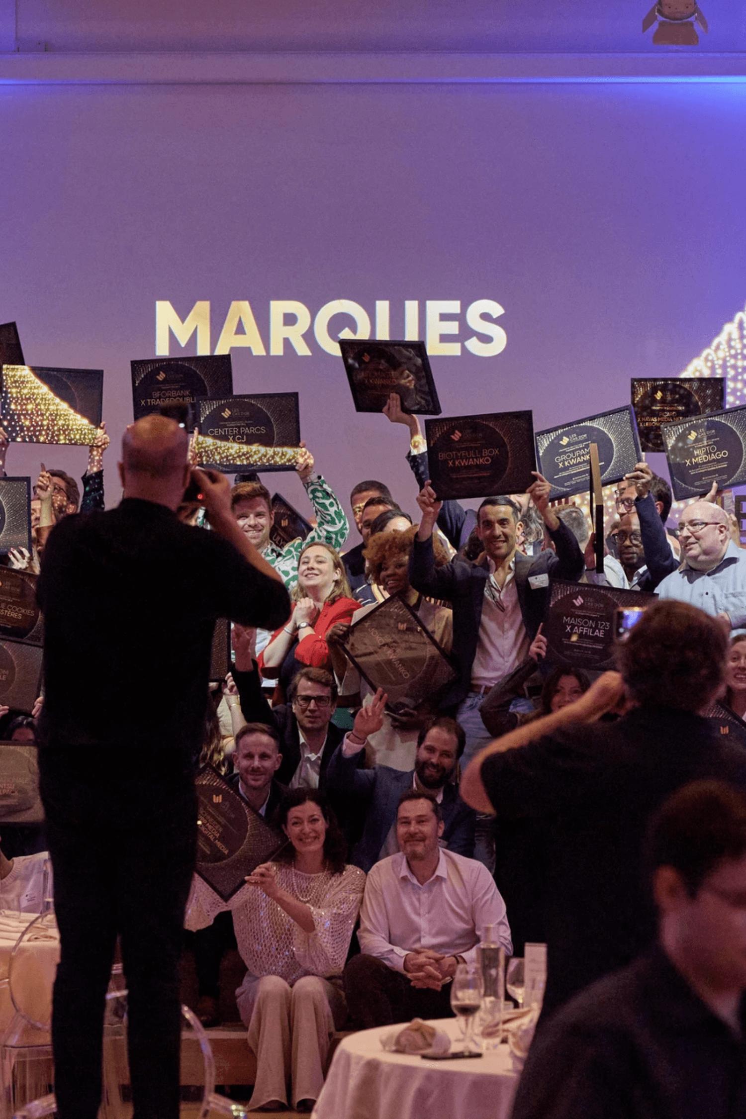 A young man in a white shirt and tie sits on the floor, surrounded by scattered papers. He looks down at a document, appearing focused and pensive.